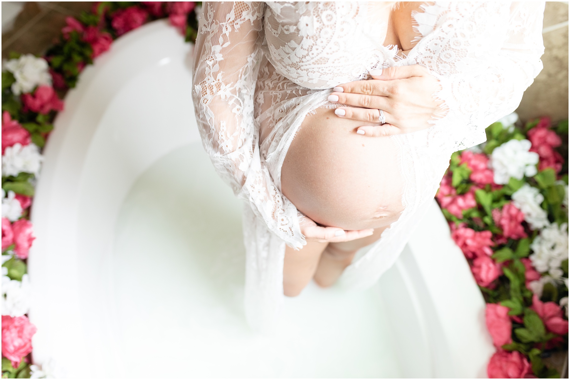 Pregnant women standing in milk bath with a lace dress and her baby bump exposed