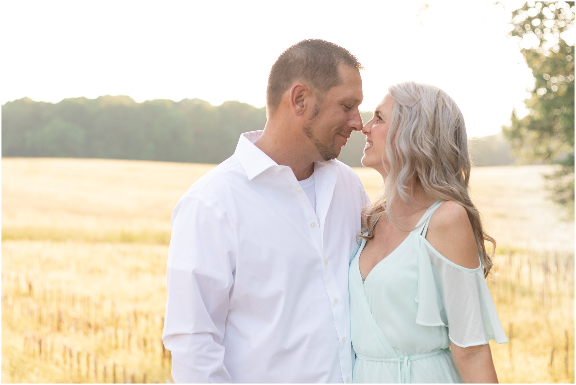 Husband and Wife touching noses in the field with golden light