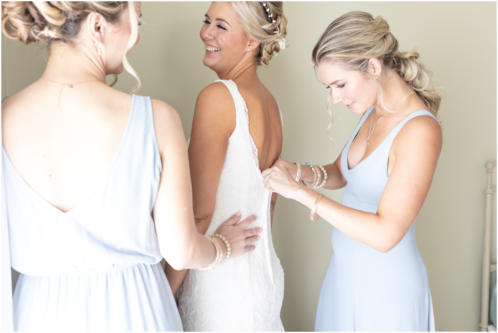 Maid of honors helping bride get into her dress