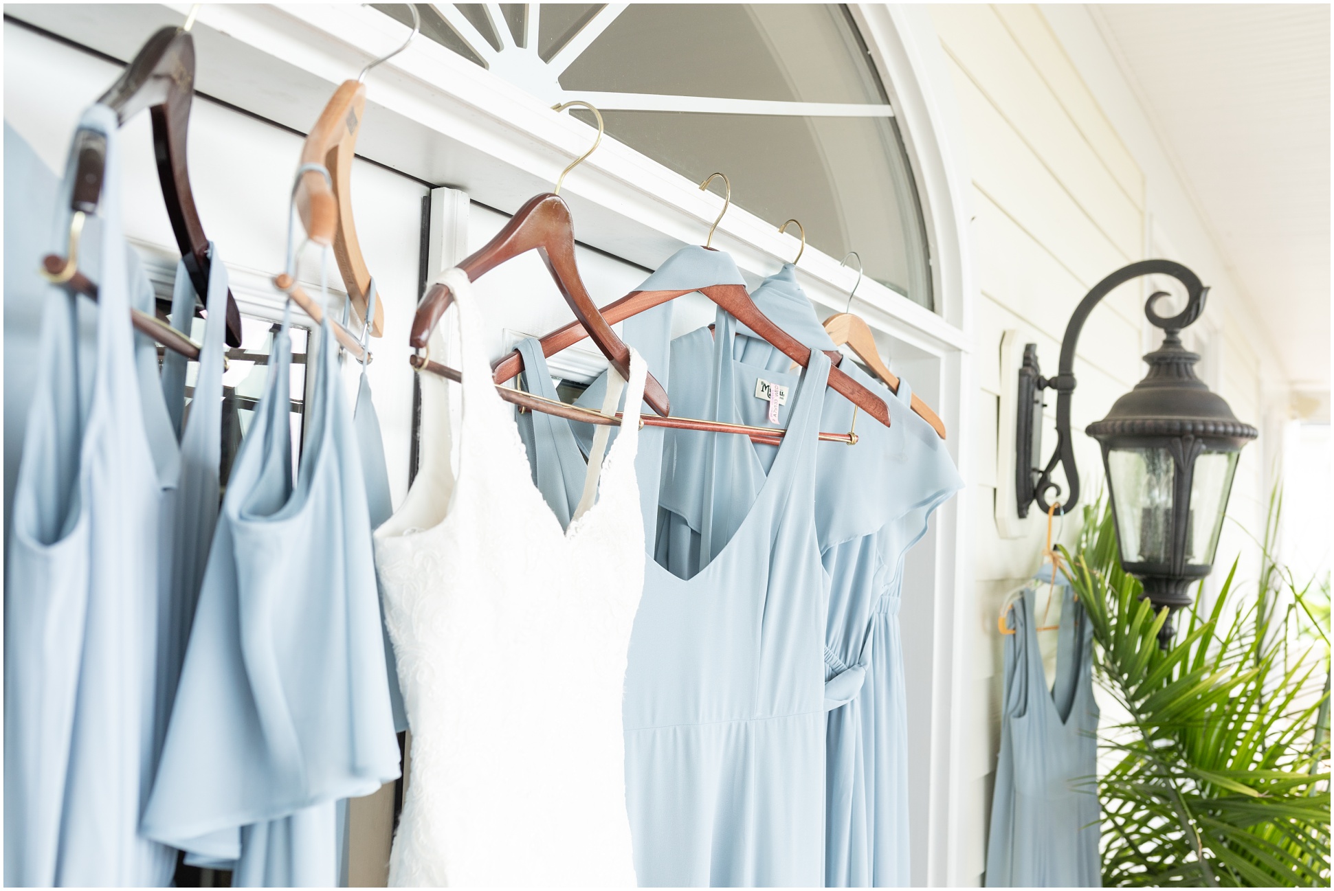 Blue Love your MuMu bridesmaids dresses hanging up next to Bridal gown