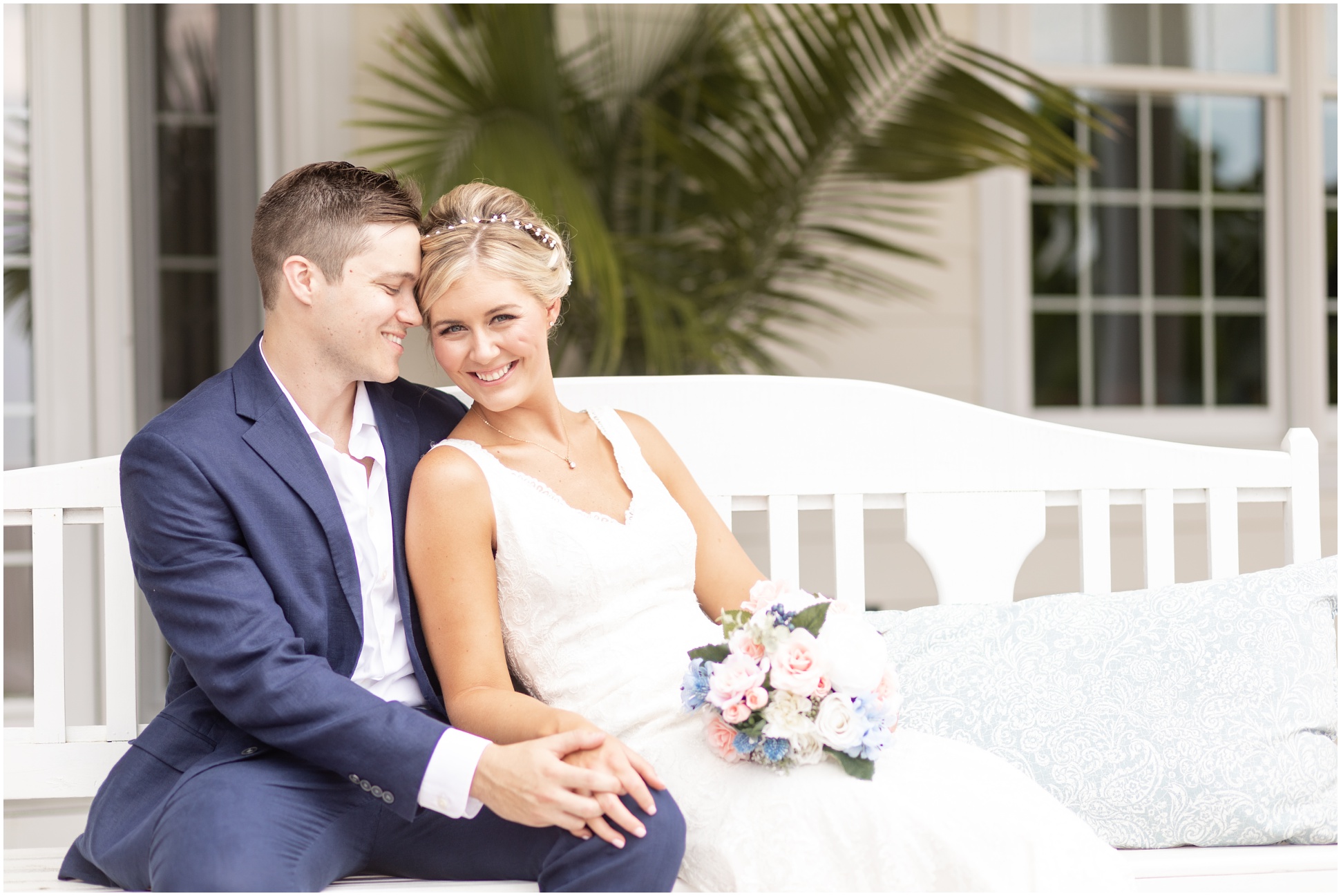 Bride and groom sitting on a bench on the front porch of the mansion
