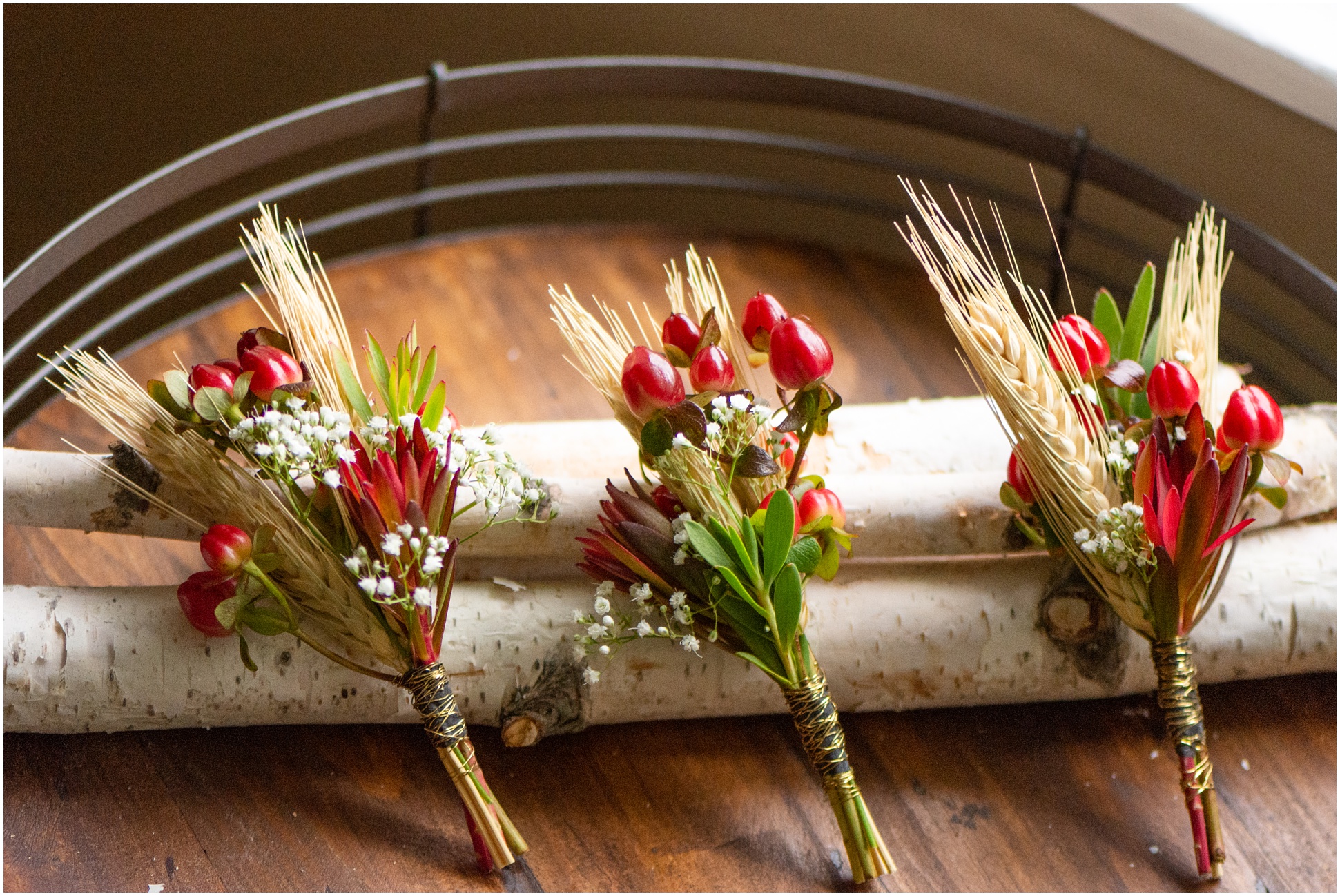 Three Boutonnieres in a row with cranberries, wheat grass, and baby's breath