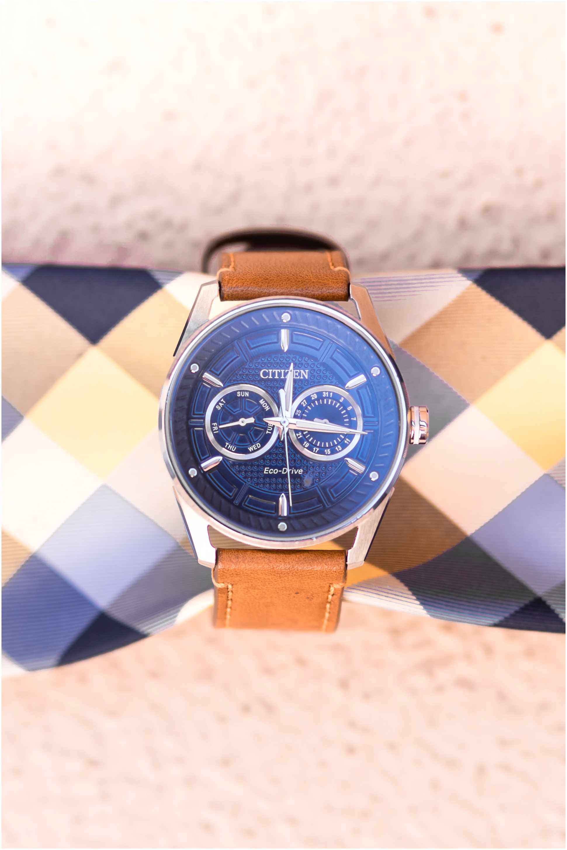 Groom's watch with brown leather wristband wrapped around blue and yellow plaid tie