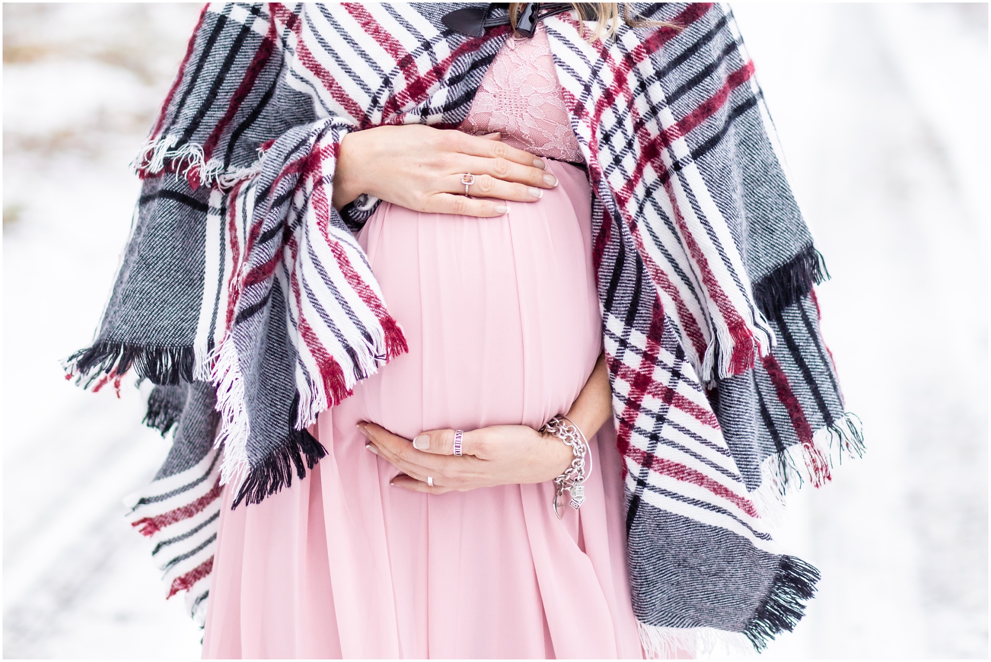 Close up shot of a baby bump with a pink flow dress and a winter shawl
