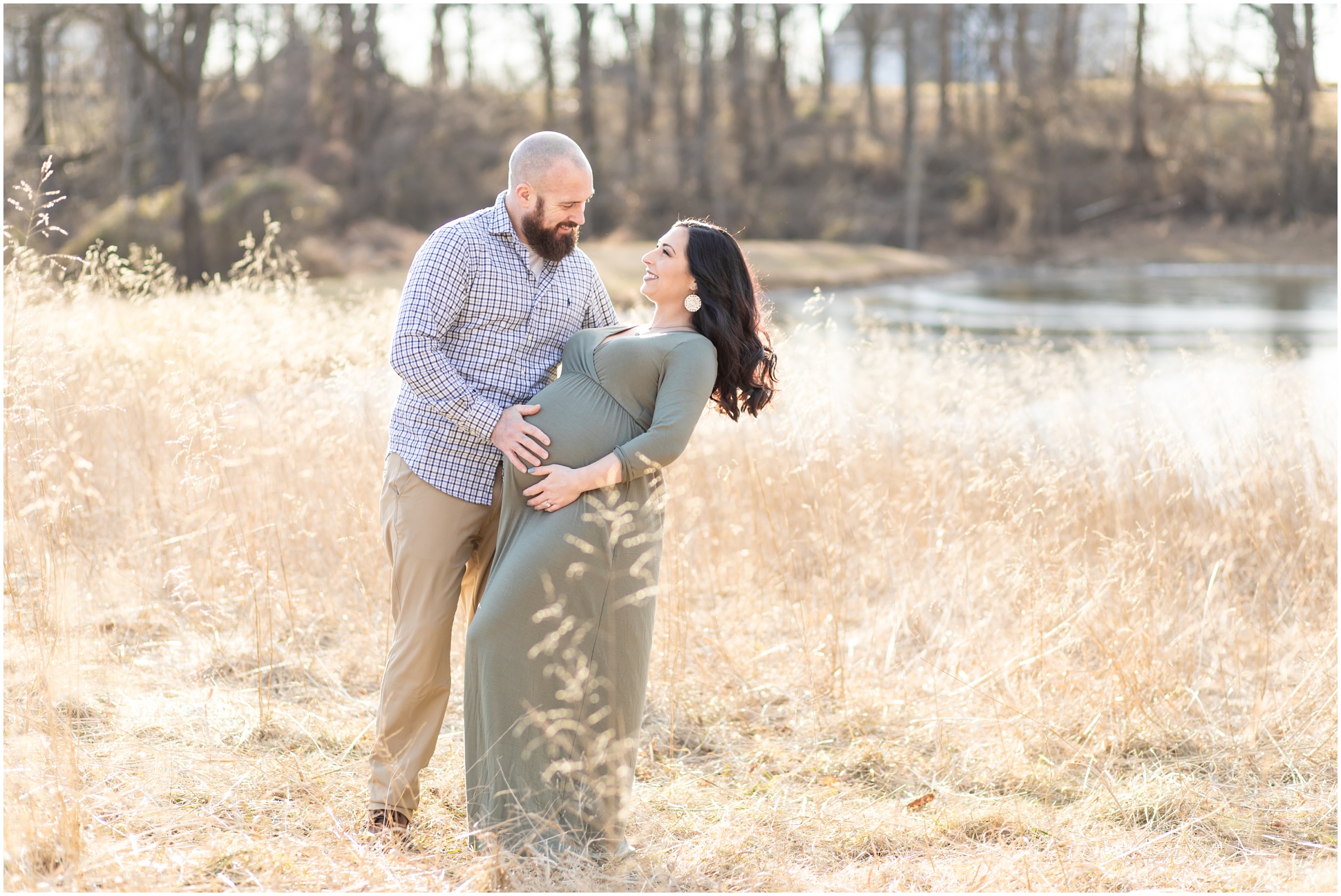 Husband dipping pregnant wife back in a field of tall grass