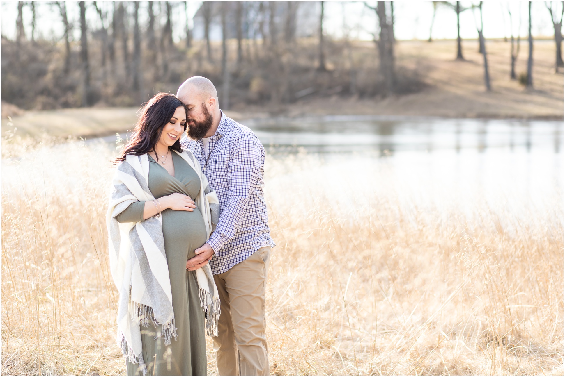 Horizontal image of pregnant couple snuggling in the golden grass