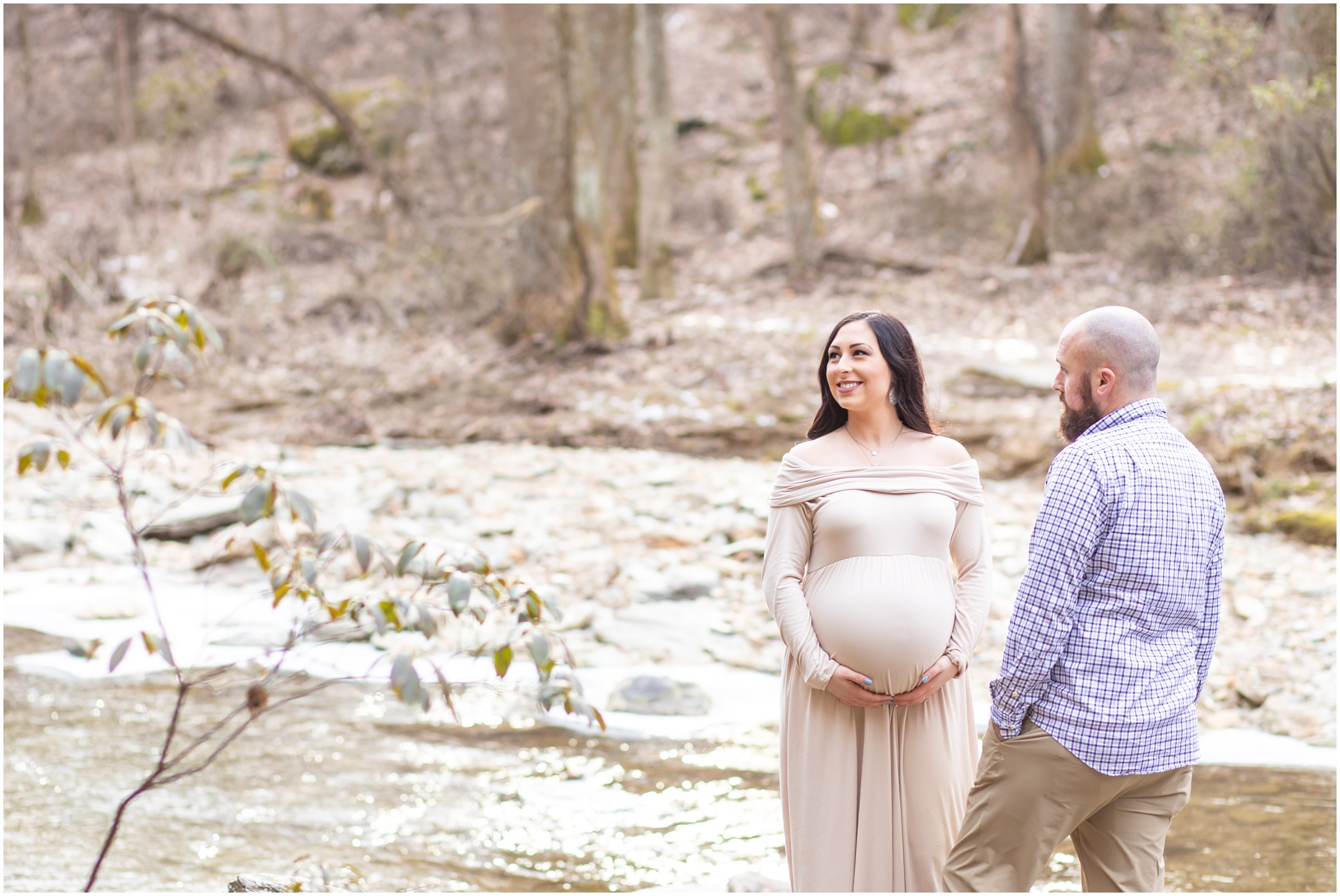 Pregnant Mom looking over into the falls as her husband adoringly glances over at her