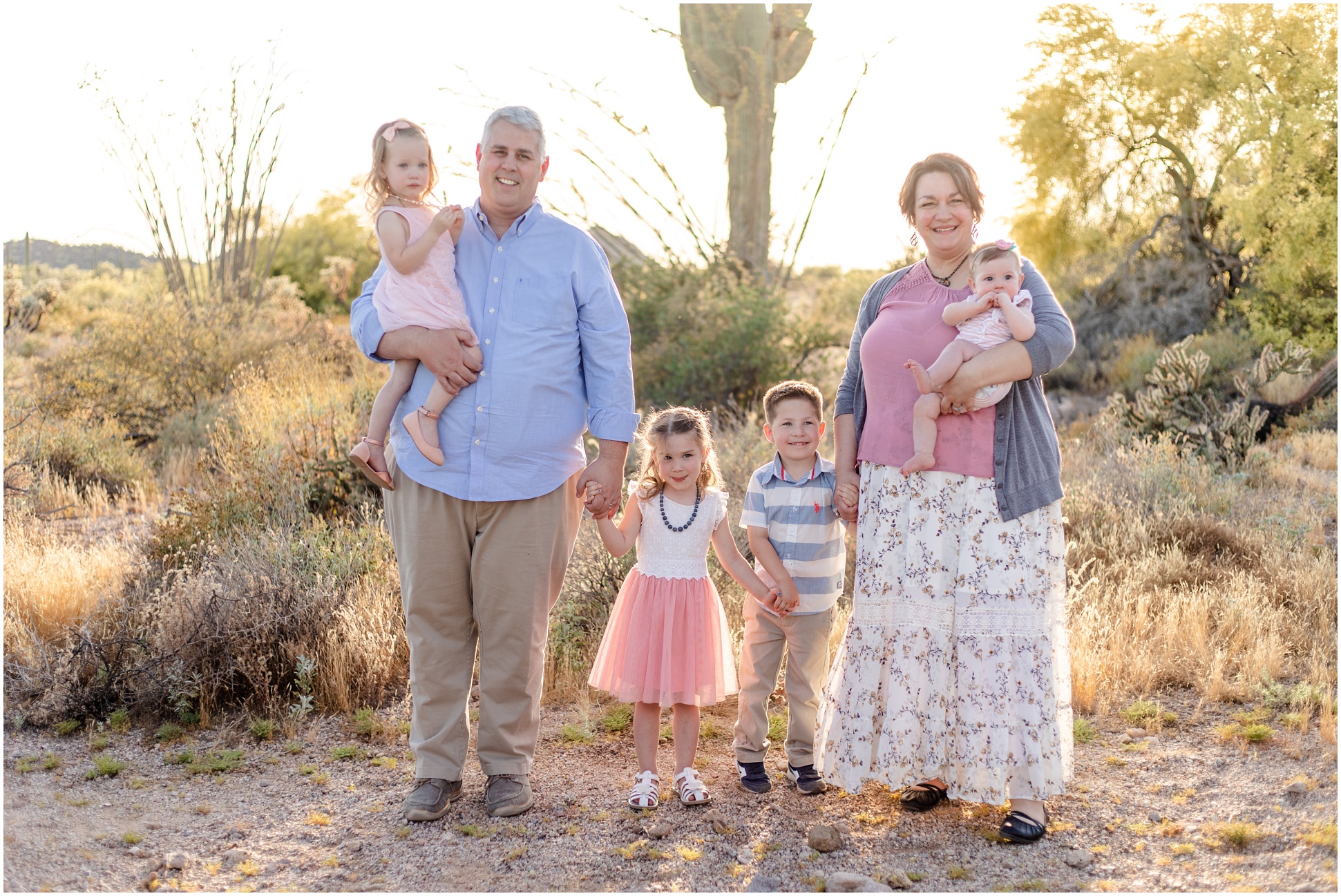 Grandparents and their grandchildren standing together in front of a saguaro cacti