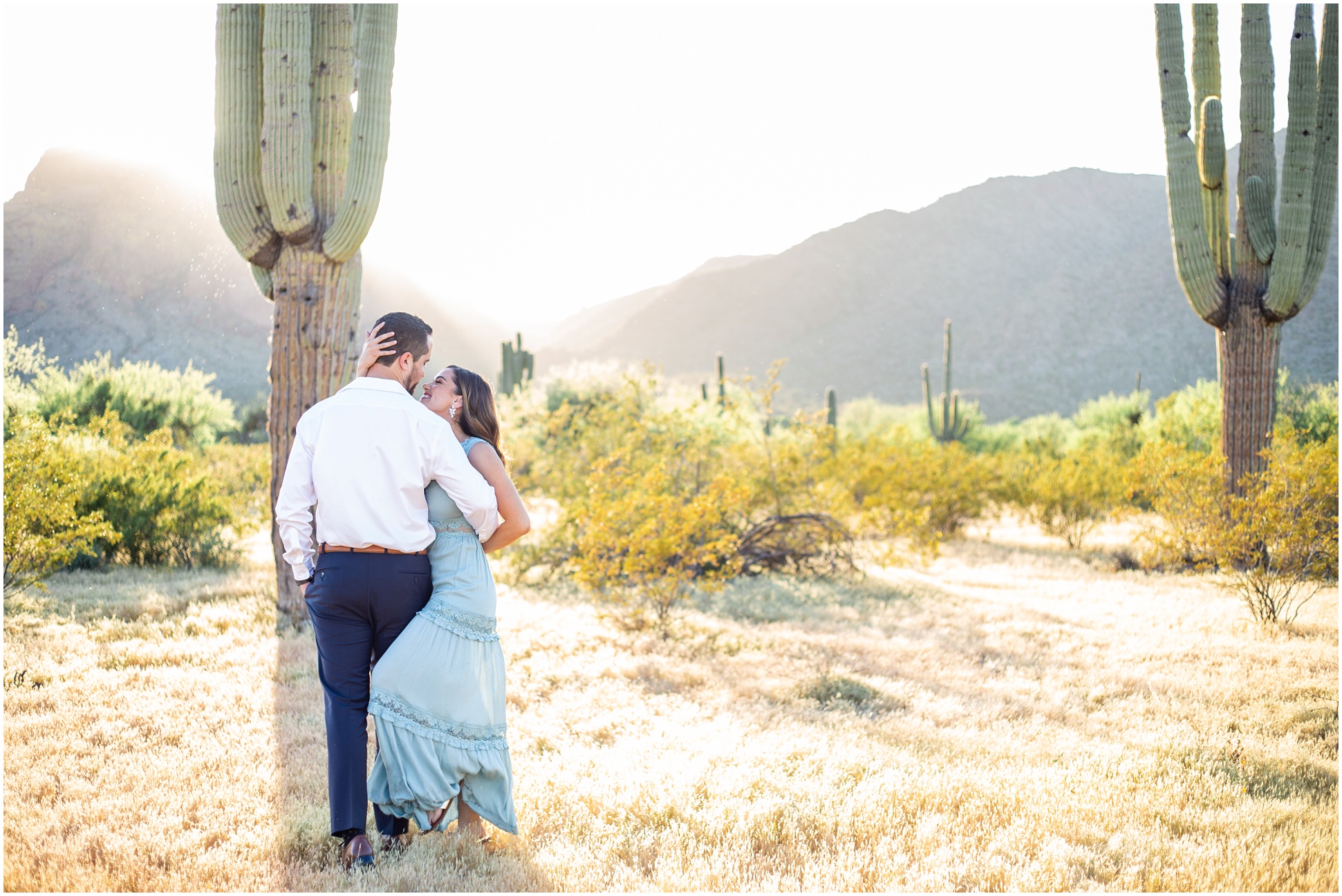 Anette and Paul De La Rosa kissing in the desert in front of a saguaro