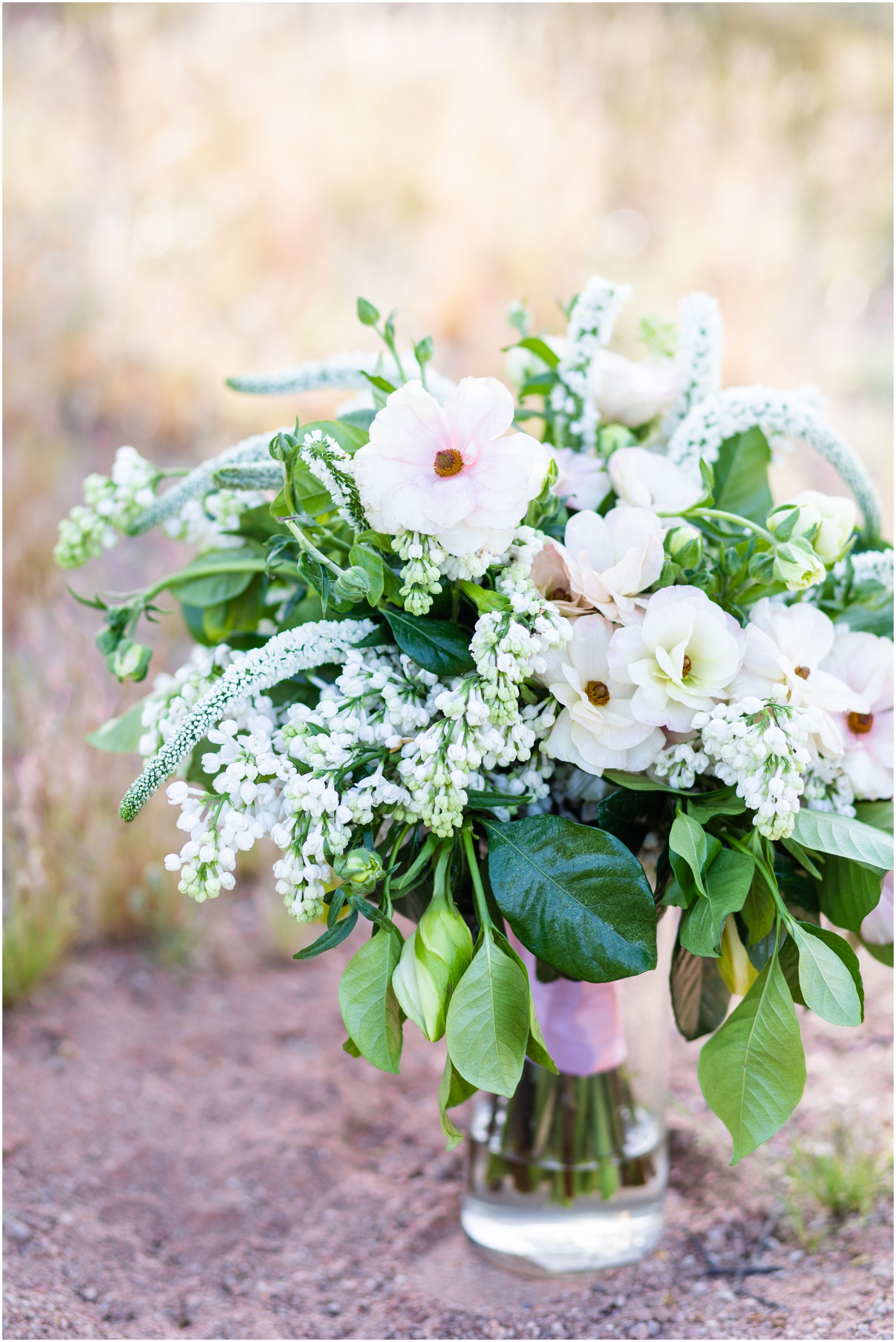 Bouquet of Garden greens and blush flowers by butterfly petals in a glass vase