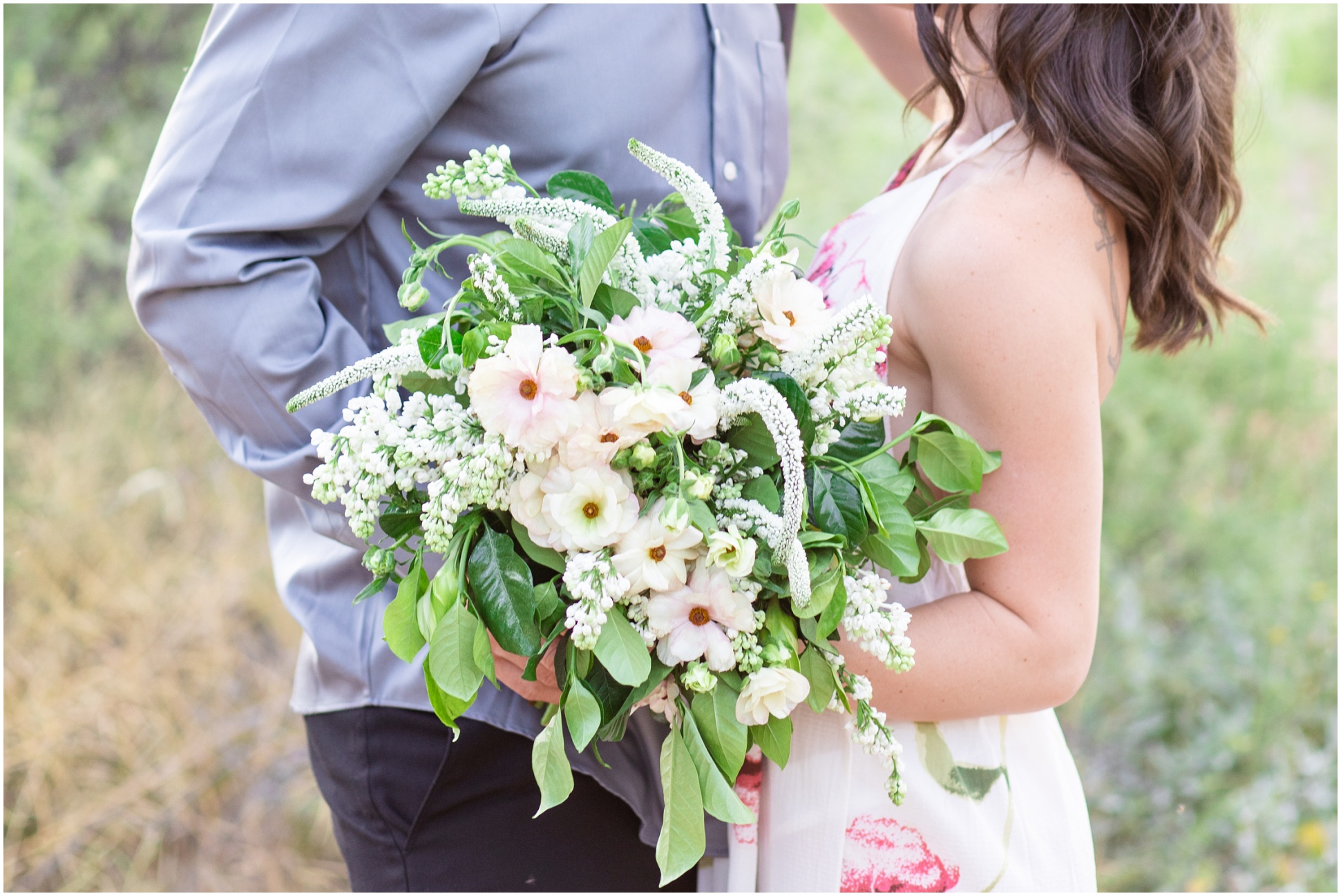 Close up of blush and green bouquet with Michael and Jessica in the background