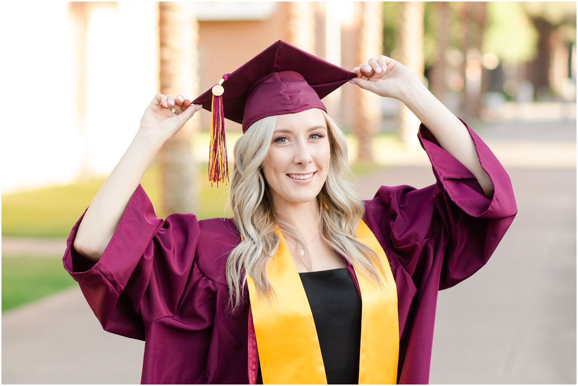 Senior holding her maroon cap on her head from ASU