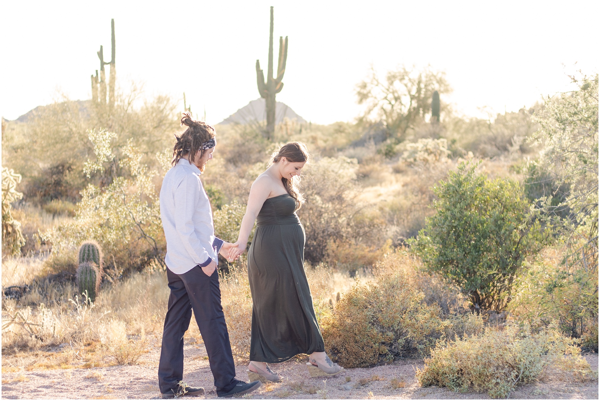 Pregnant Woman guiding her husband through the desert in green maternity dress