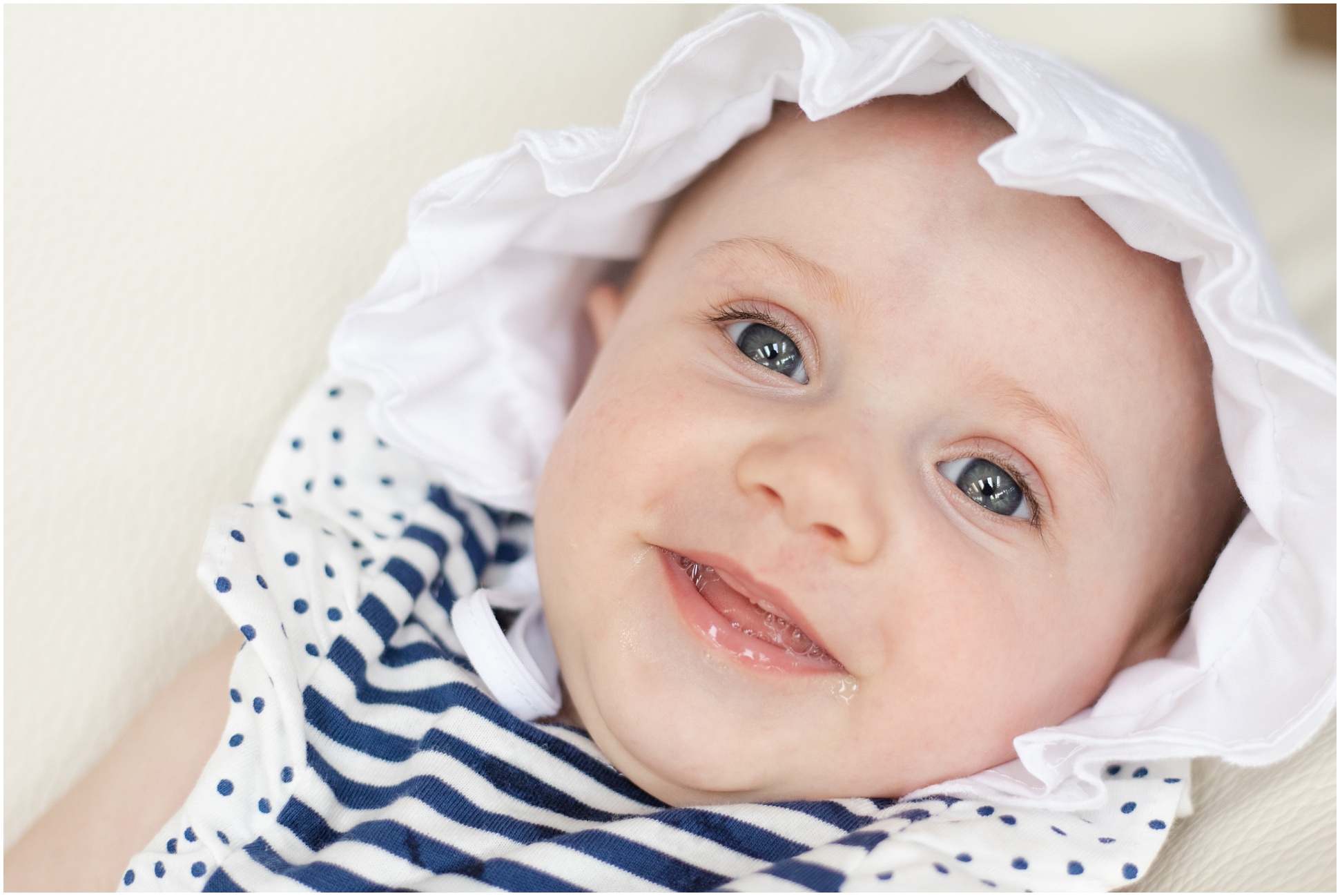 Baby wearing a white bonnet and smiling at the camera
