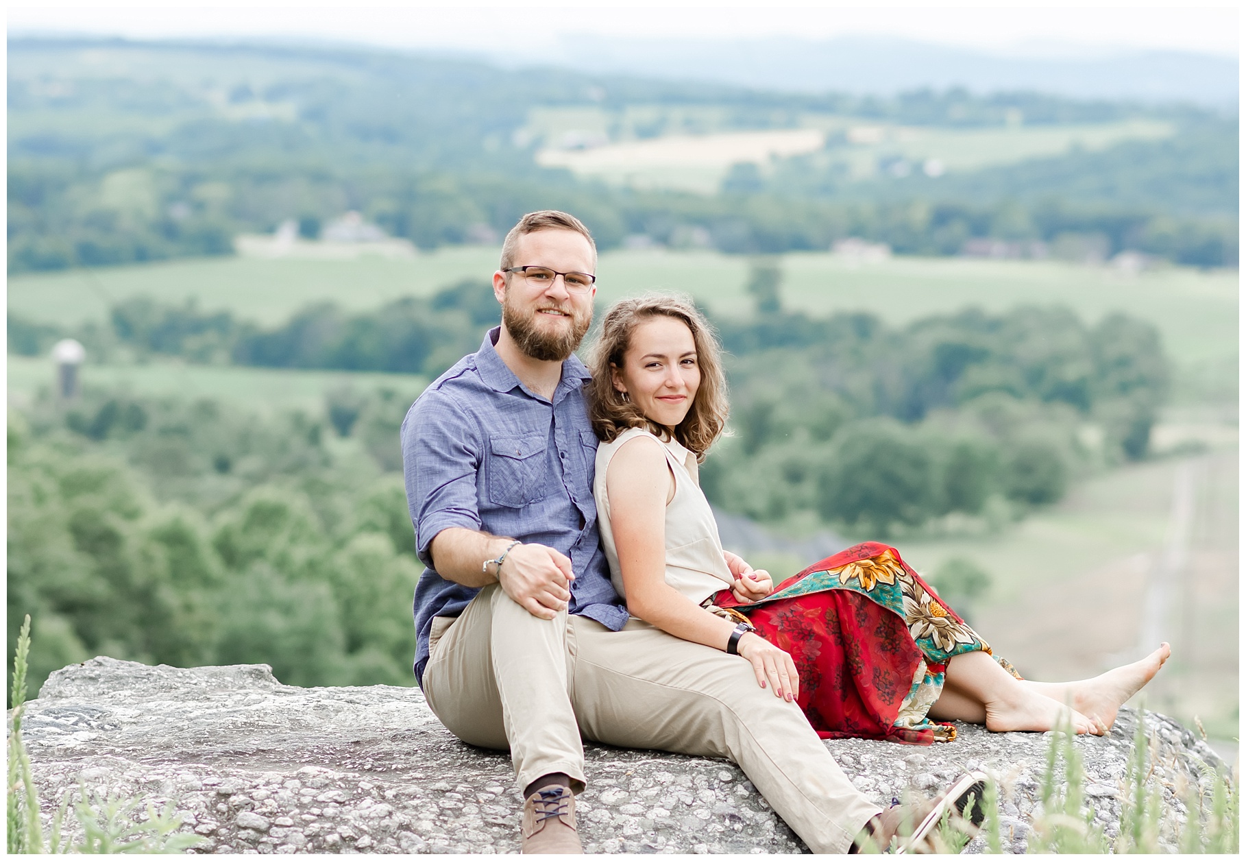 Couple sitting on rock overlooking farmland