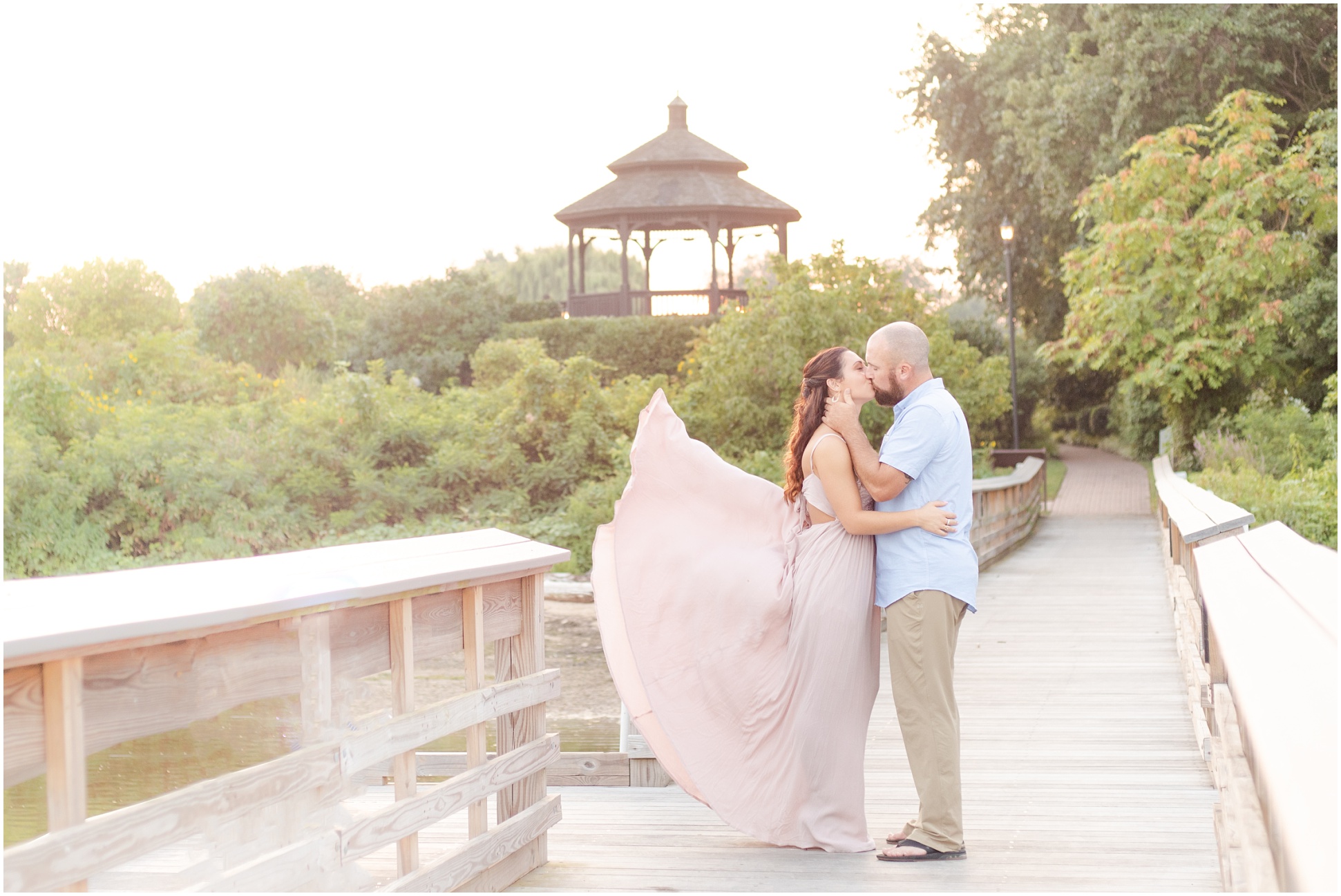 Blush dress blowing in the wind as bride and groom kiss during their engagement session at Swan Harbor Farm