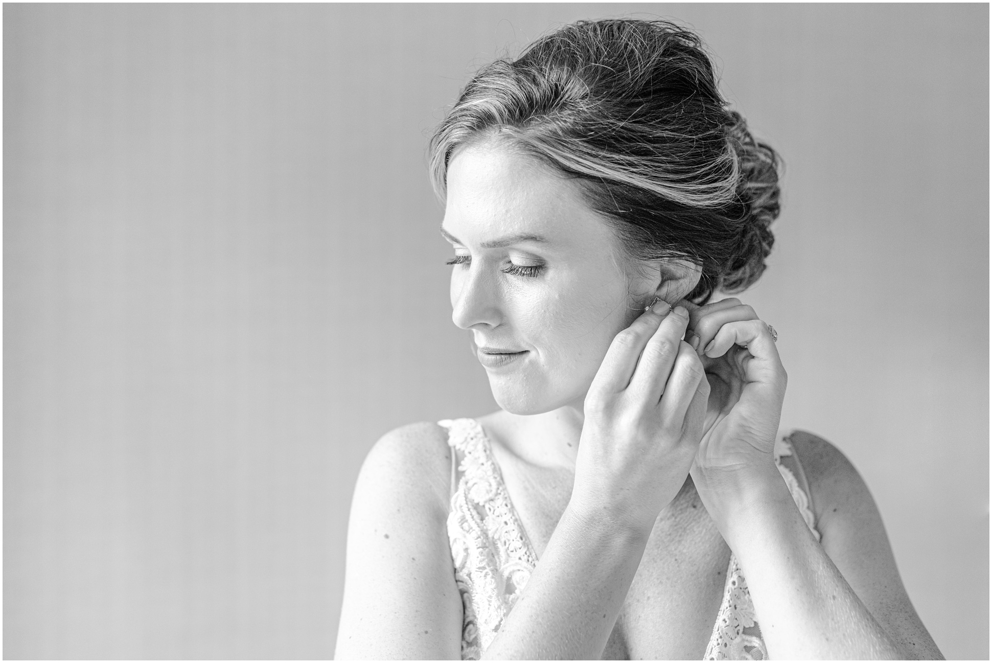Black and White Image of bride putting on earrings