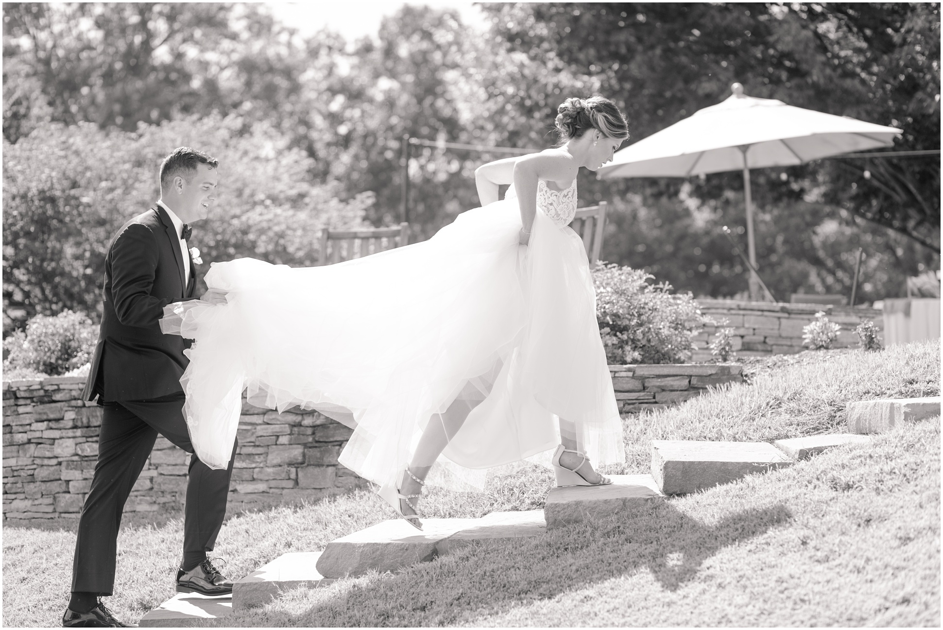 Black and White image of bride and groom walking up their steps at Eagles Nest Country Club