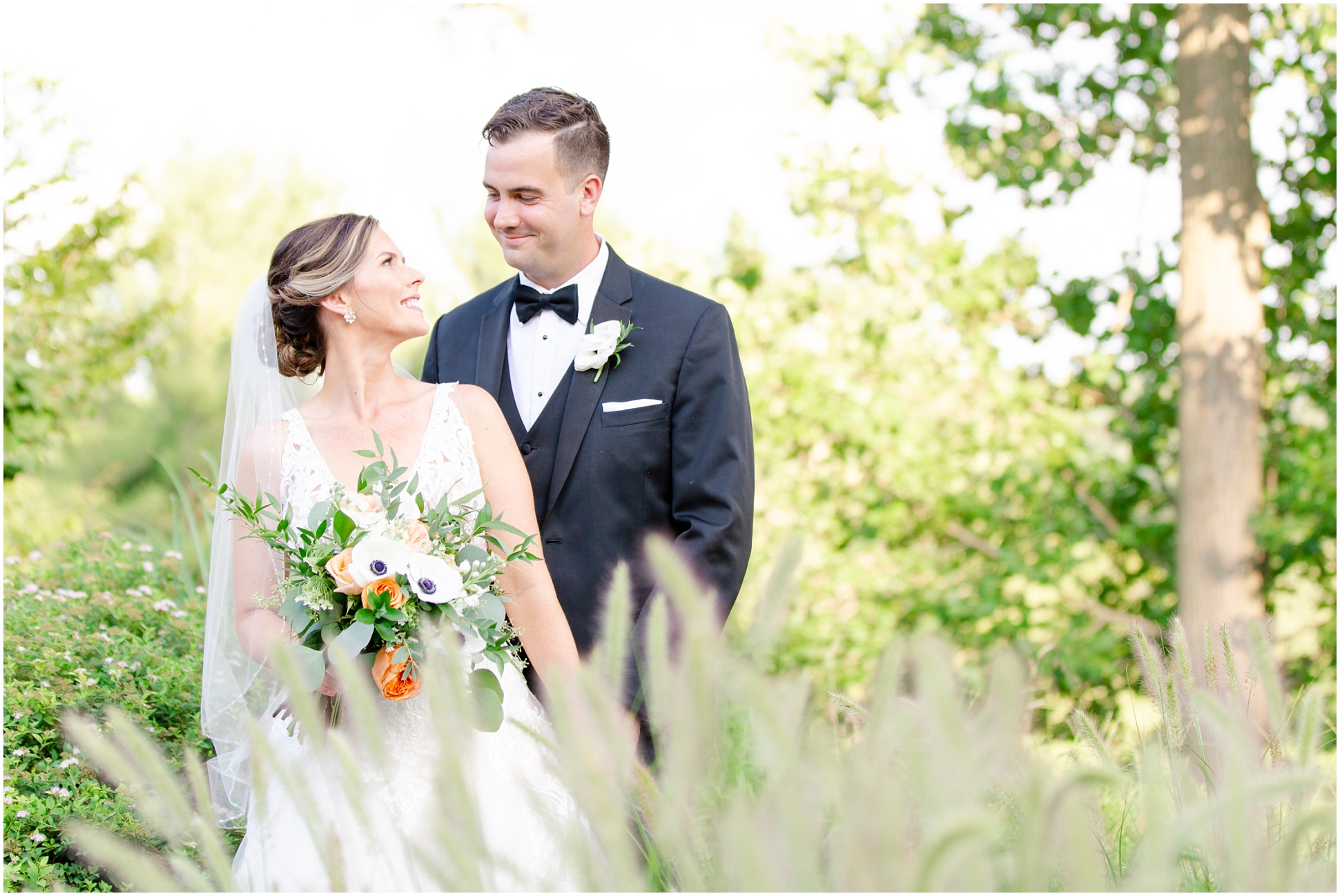 The bride and groom giggling at each other behind the cat tails on the golf course