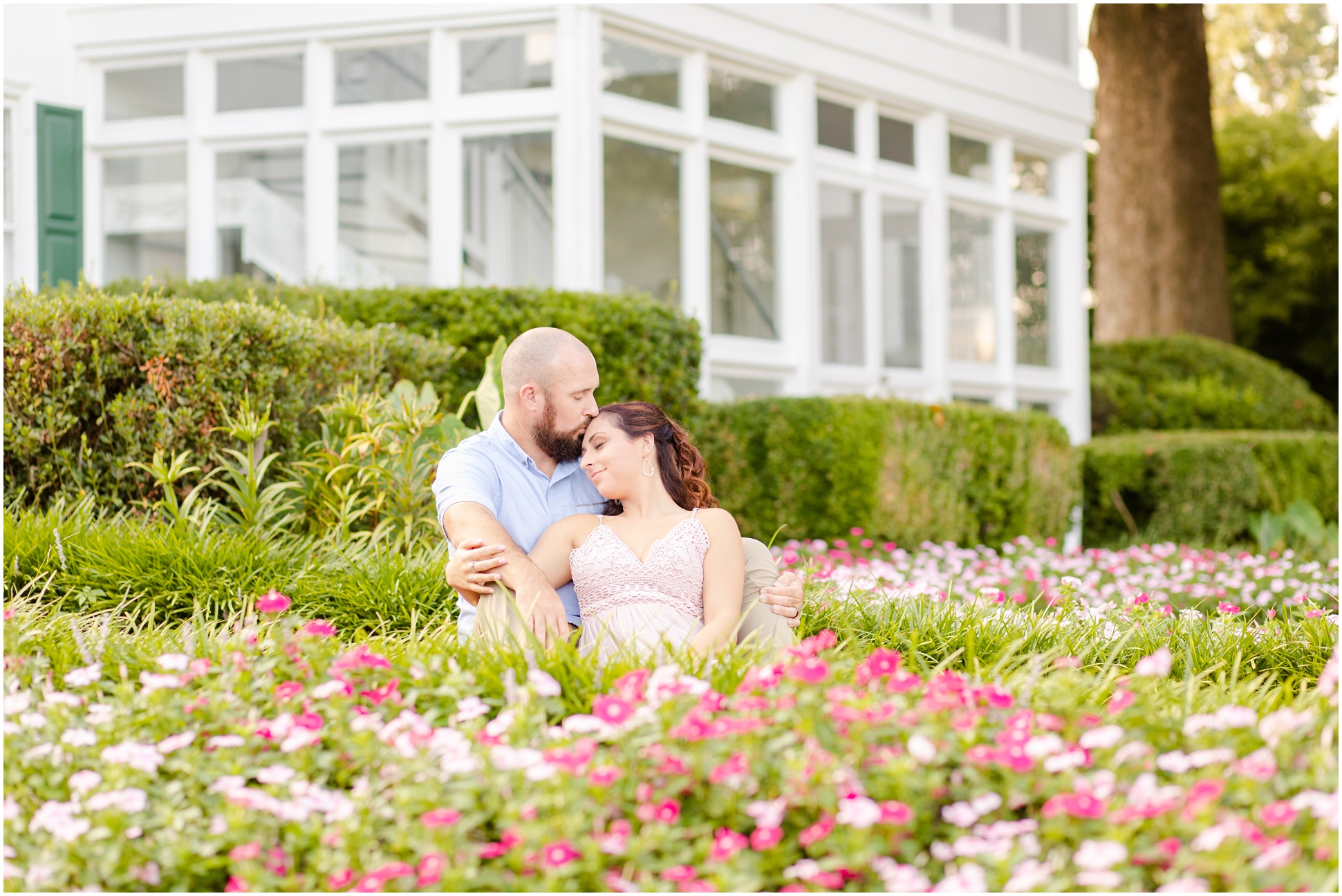 Bride and groom snuggling in the garden of dark and light pink flowers