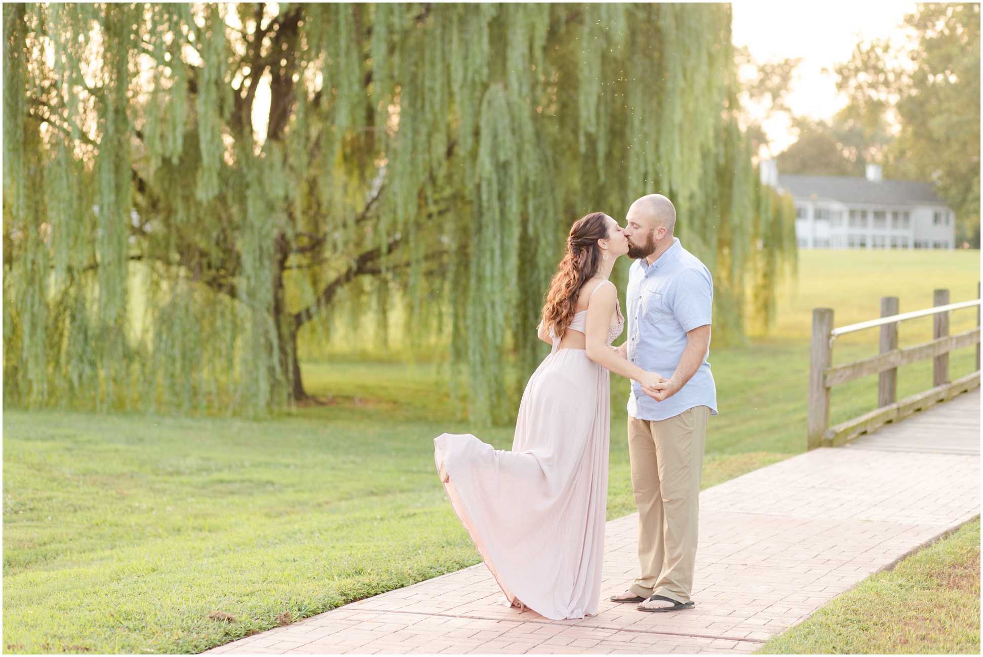 Couple kissing in front of the willow tree and the sunset on swan harbor farm