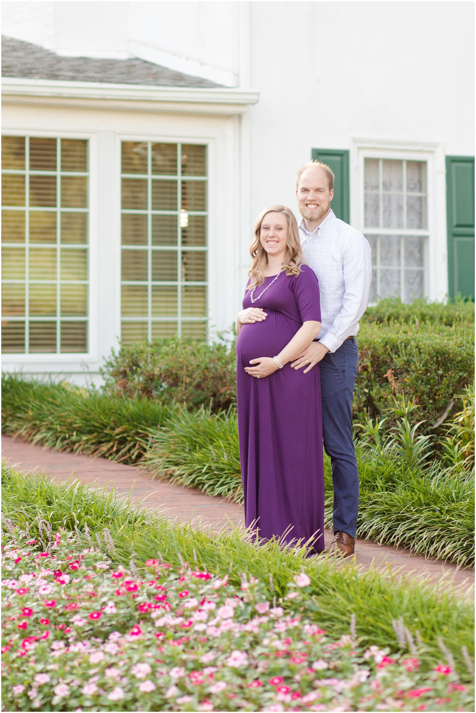 Pregnant woman wearing purple dress and holding her belly, standing in front of her husband