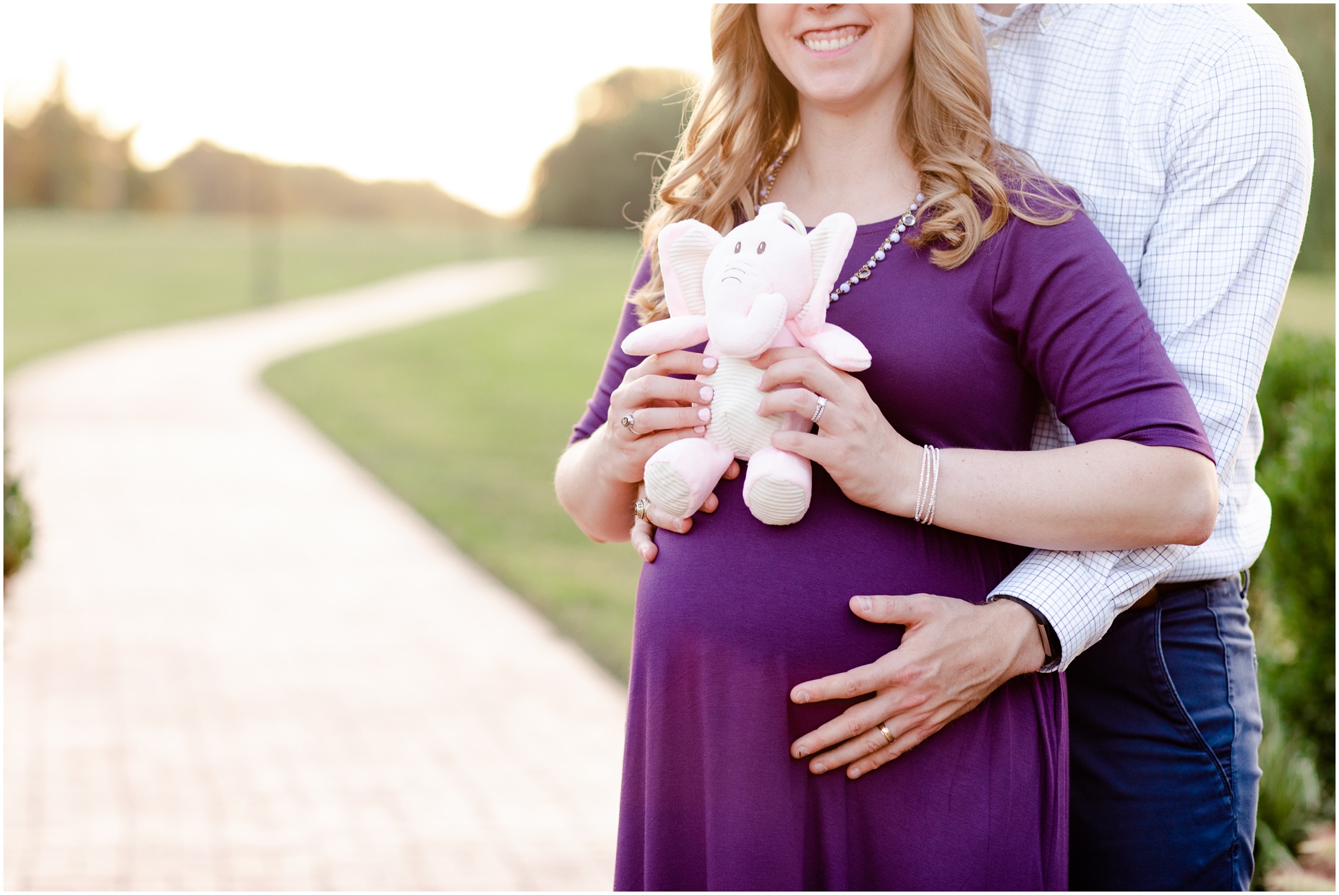 Pregnant couple holding a pink elephant for their maternity session