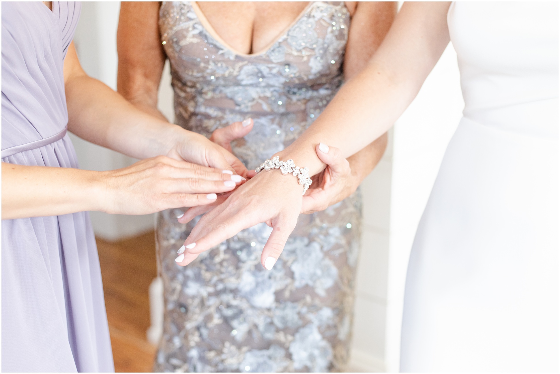 Mother of the bride and maid of honor helping bride put on bracelet