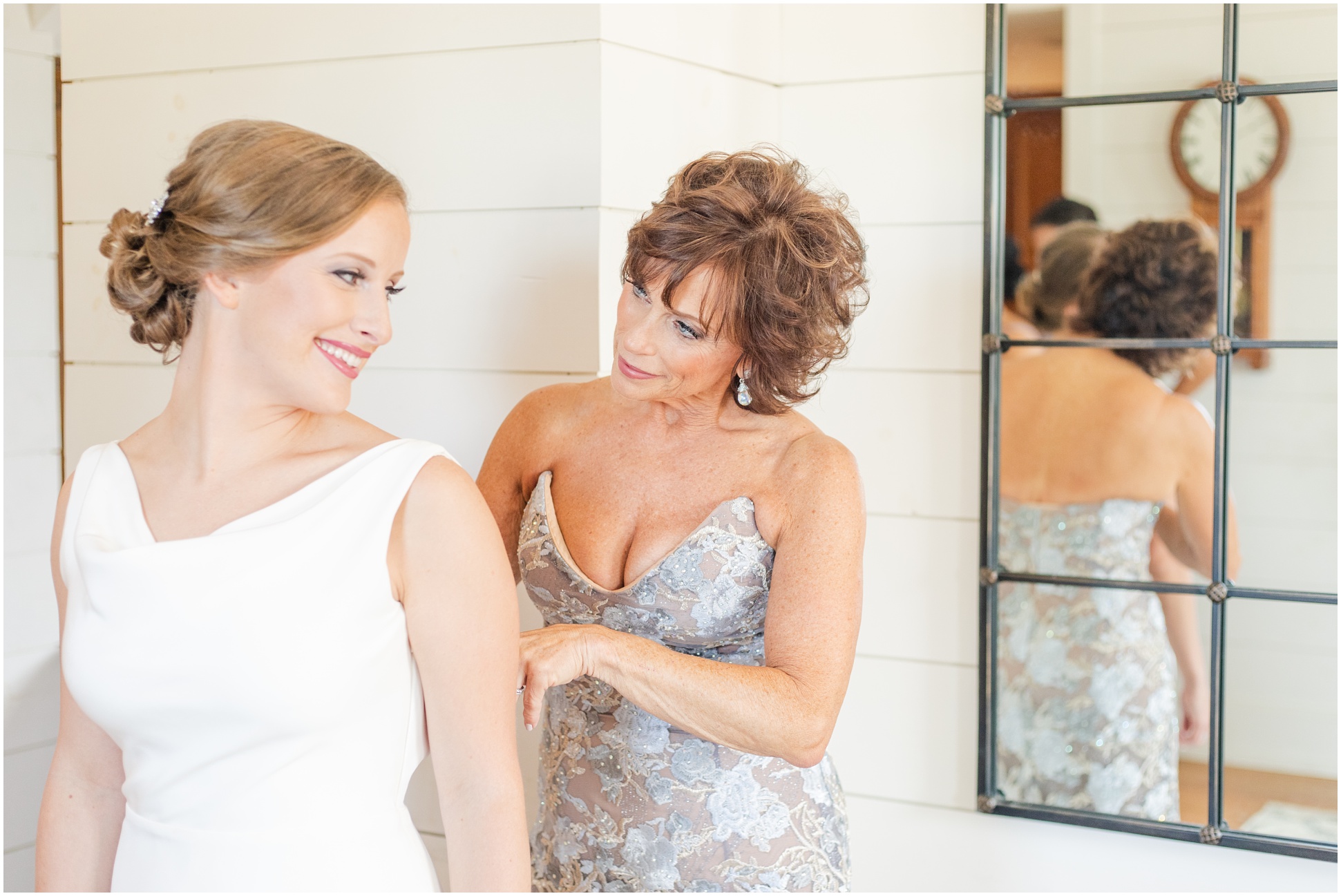 Mother of the bride wearing a gown and helping her daughter into her wedding dress