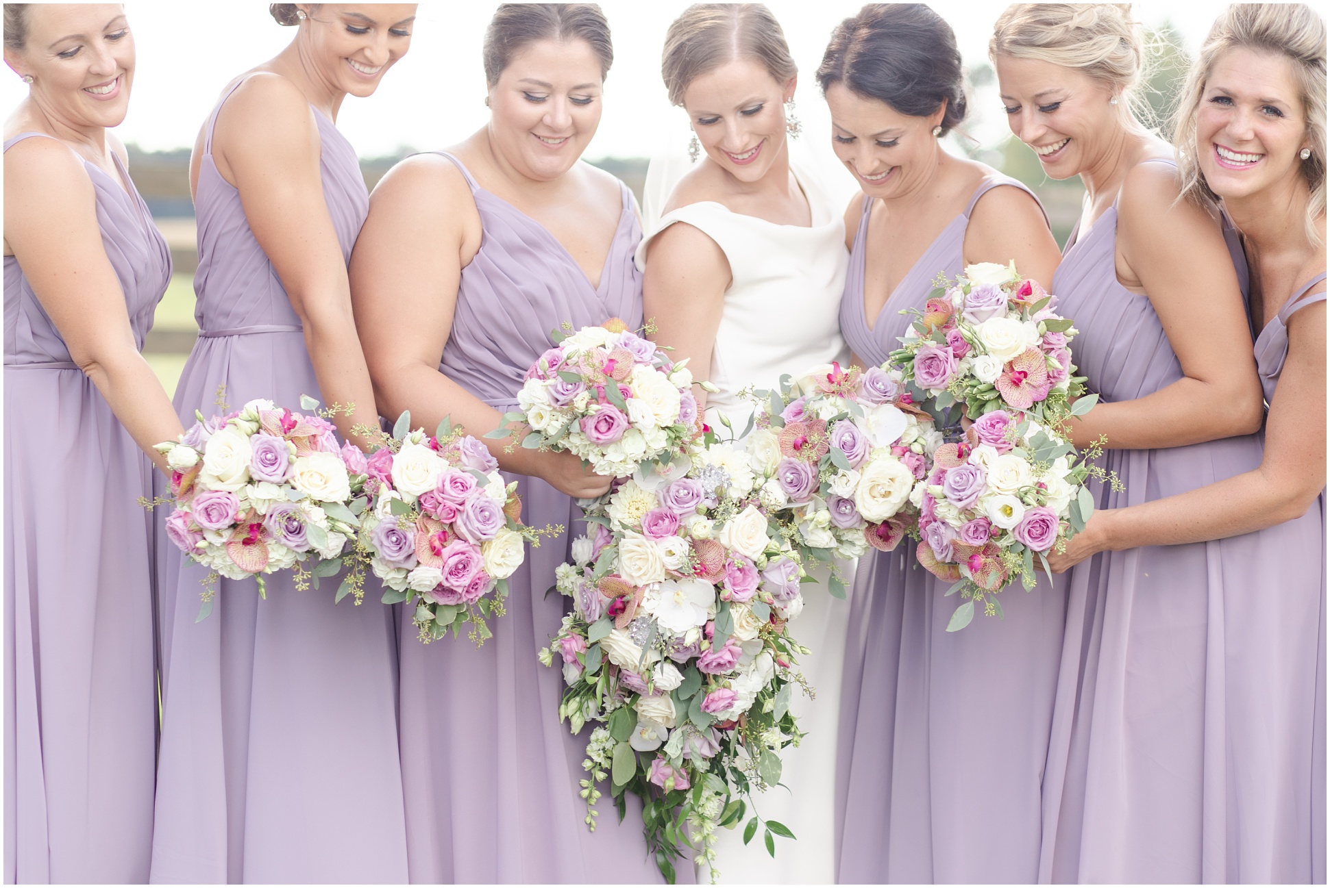 Bride with bridal party holding bouquets and looking down
