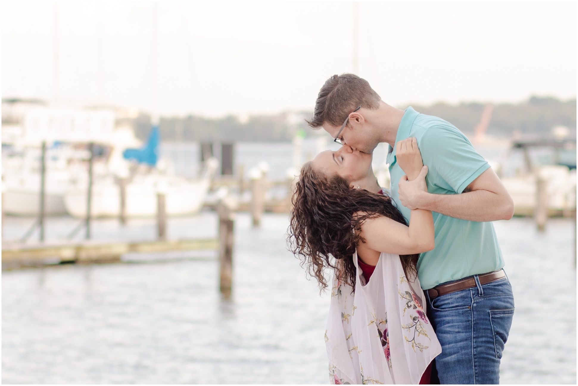 An engaged couple kissing in front of the boat dock at Nick's Fish House