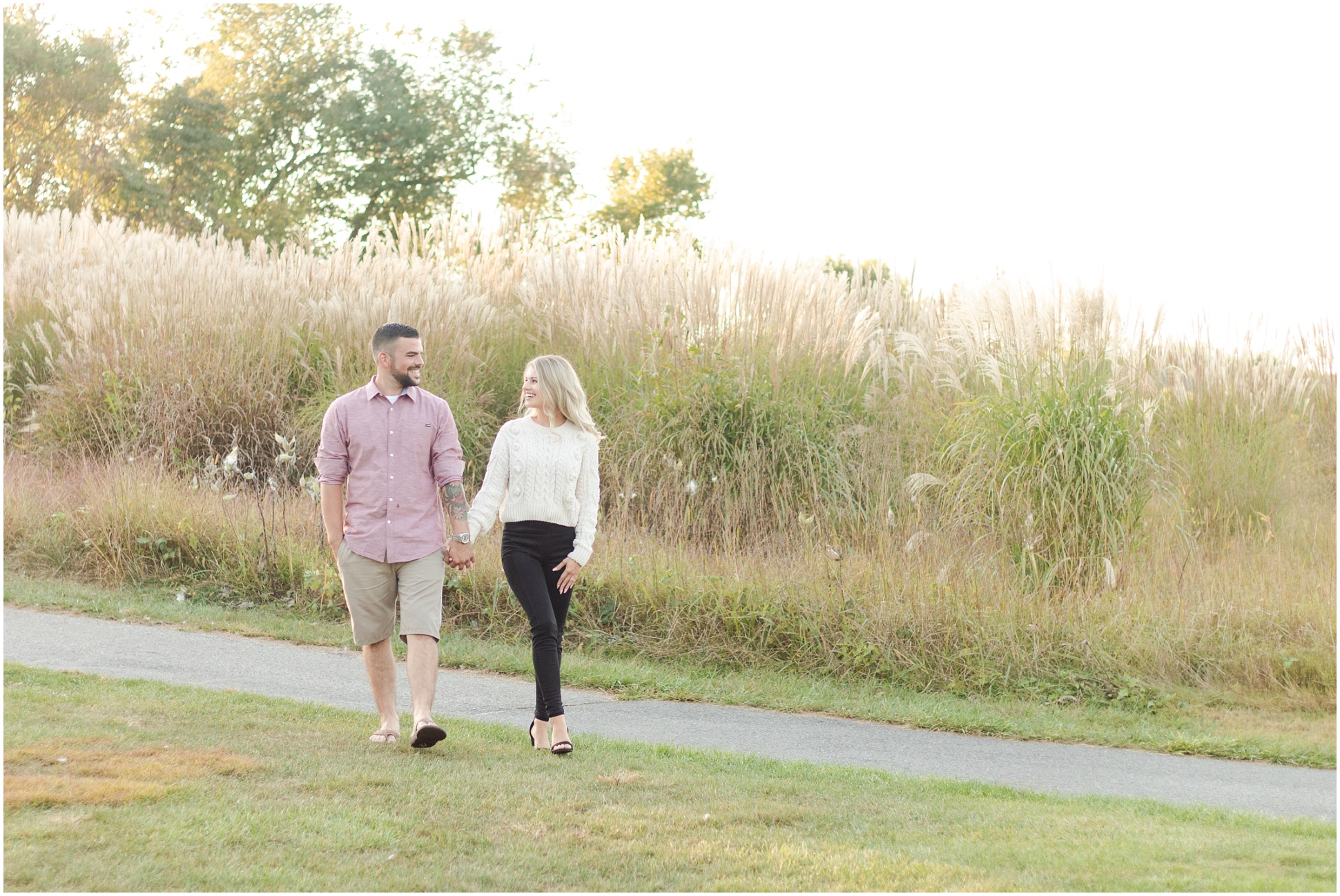Engaged couple walking on the golf course in front of the golden wheat grass.