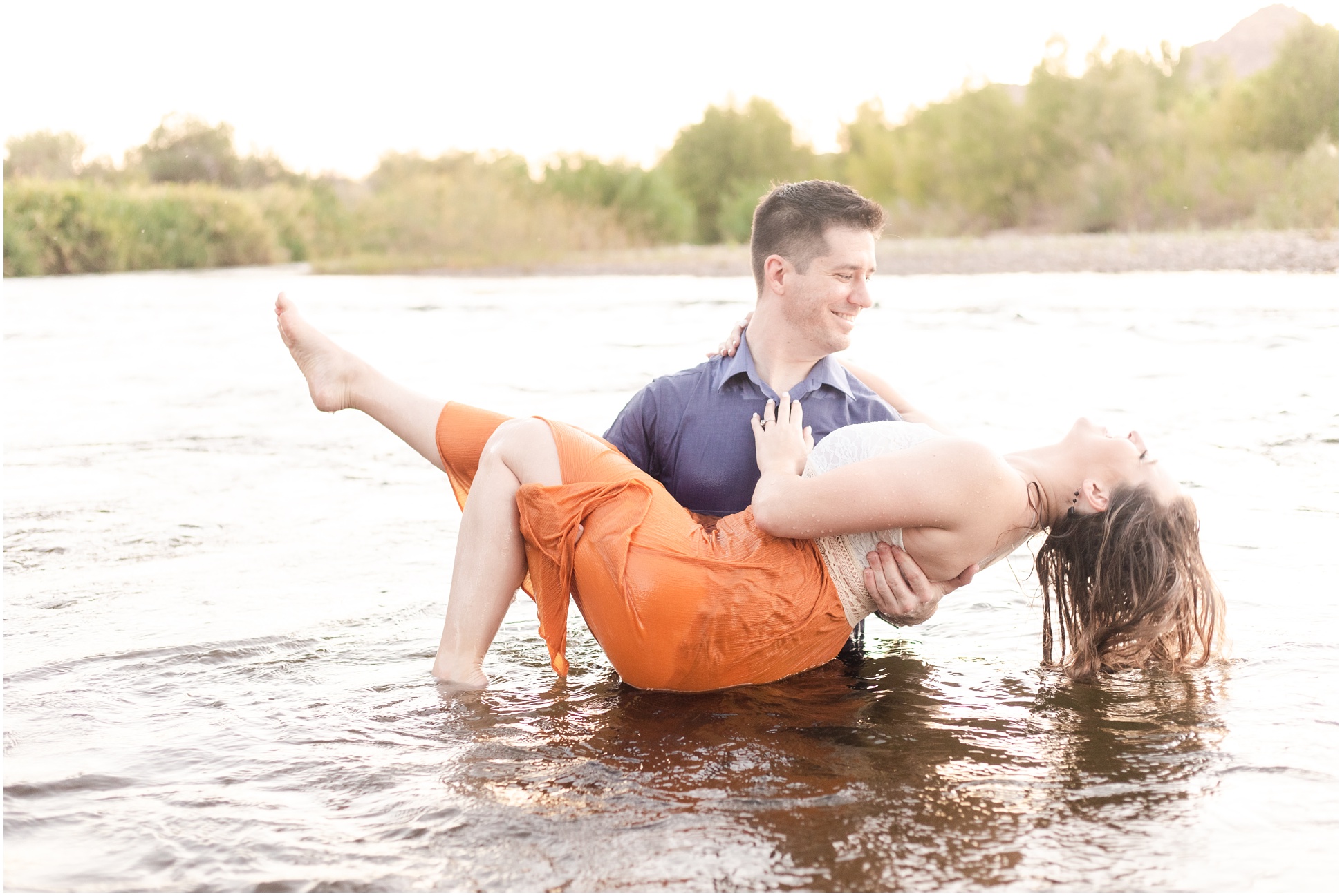 man carrying woman in orange and white dress in salt river