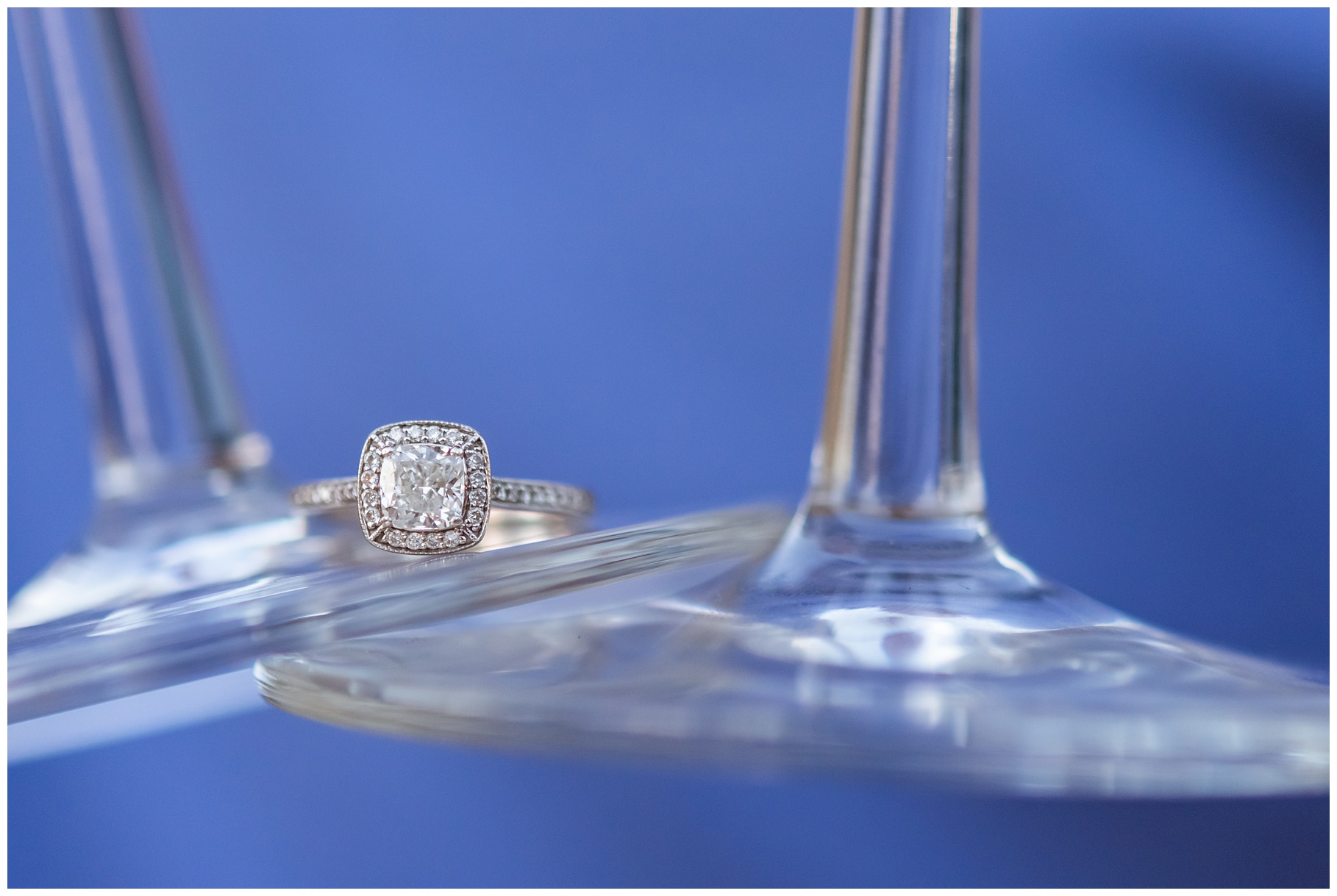 Engagement ring resting on wine glasses