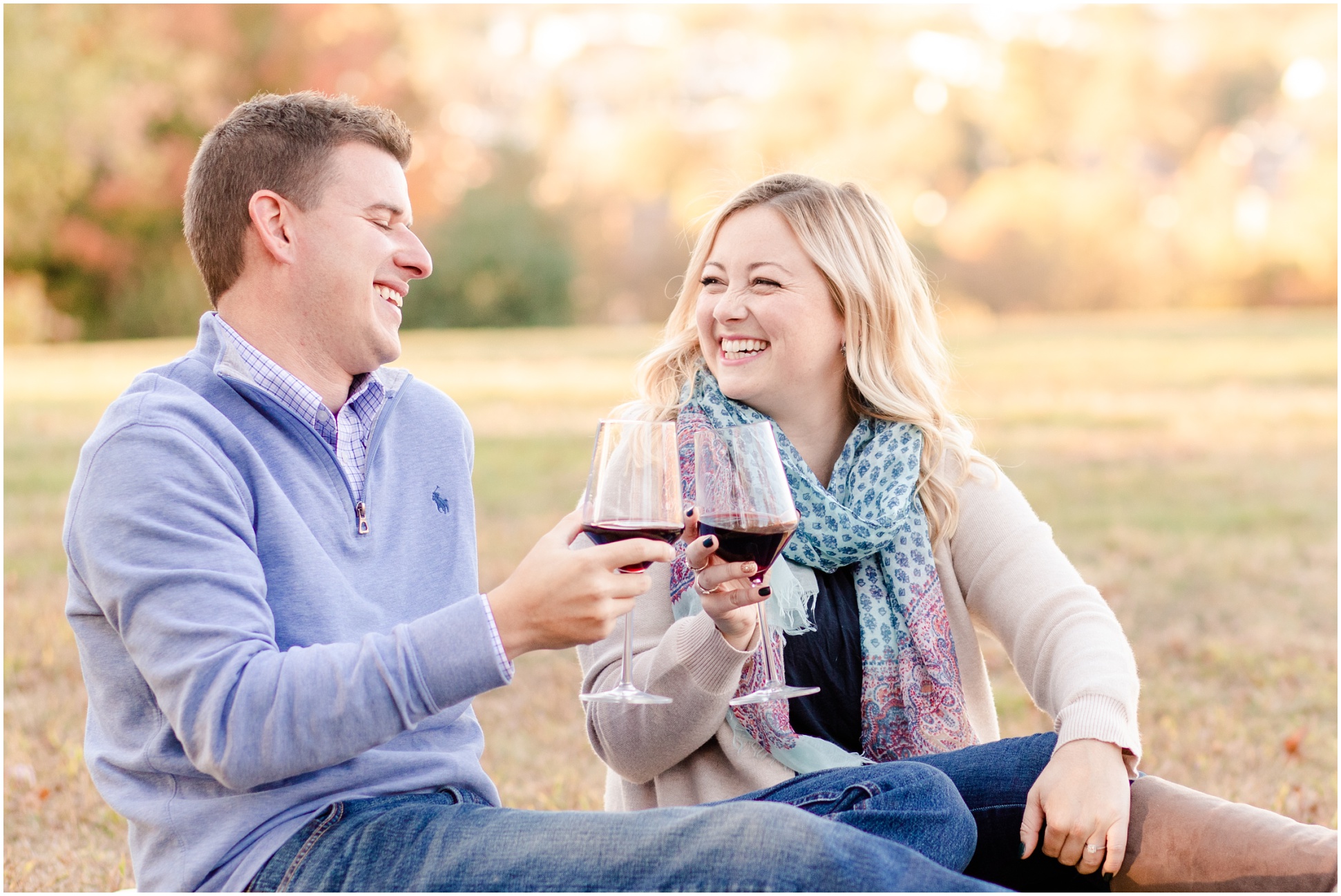 Couple laughing at each other while making a toast with red wine 
