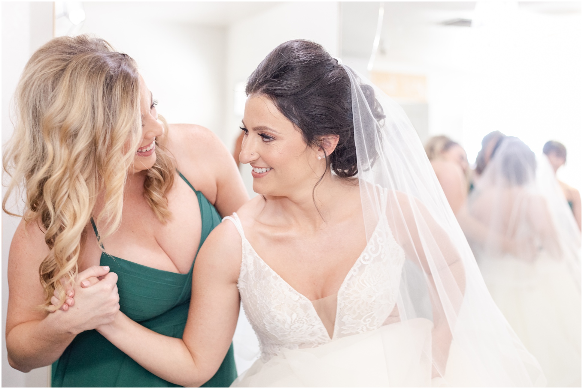 Bridesmaid holding brides hand in dresses smiling at each other