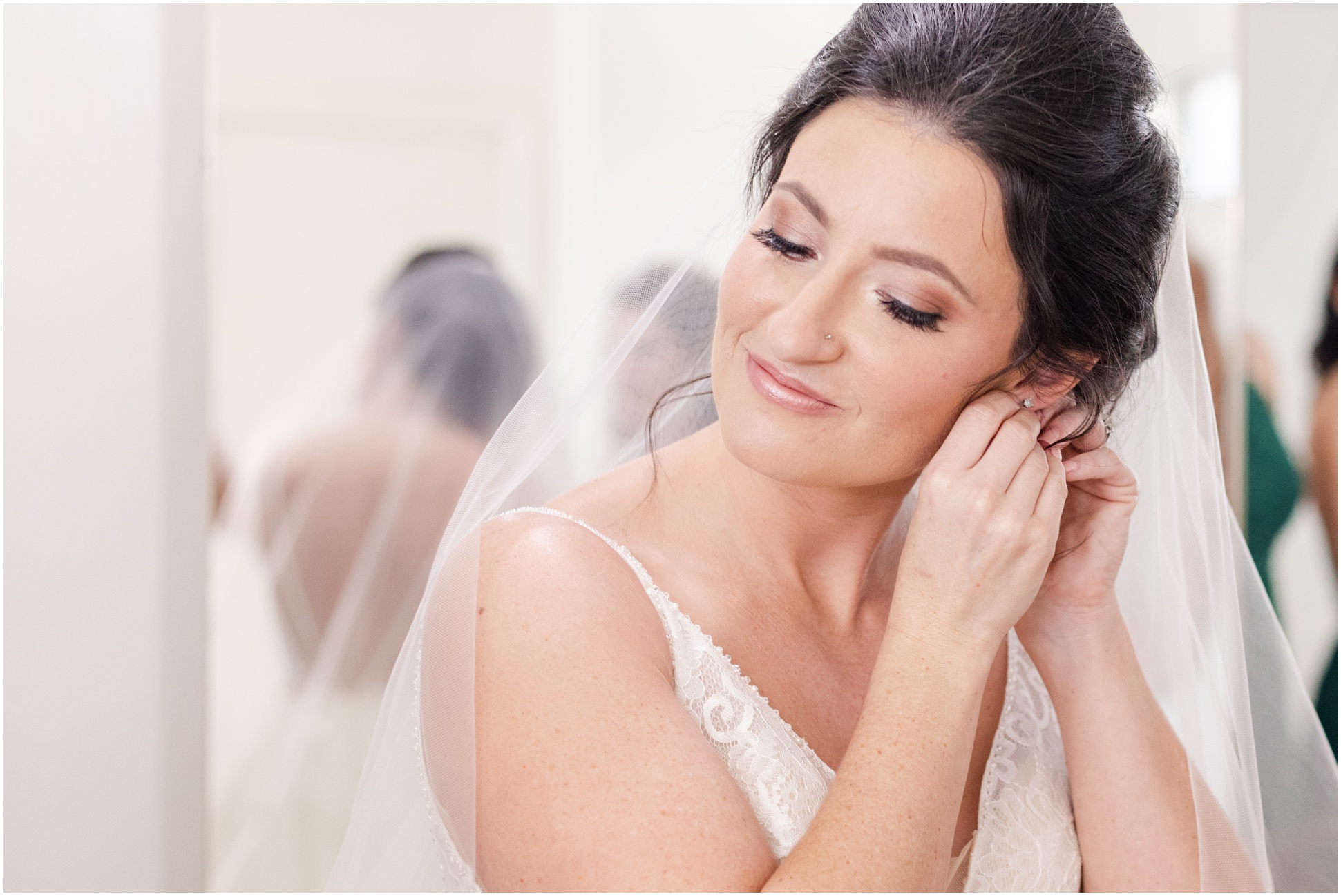 bride smiling while putting earrings 