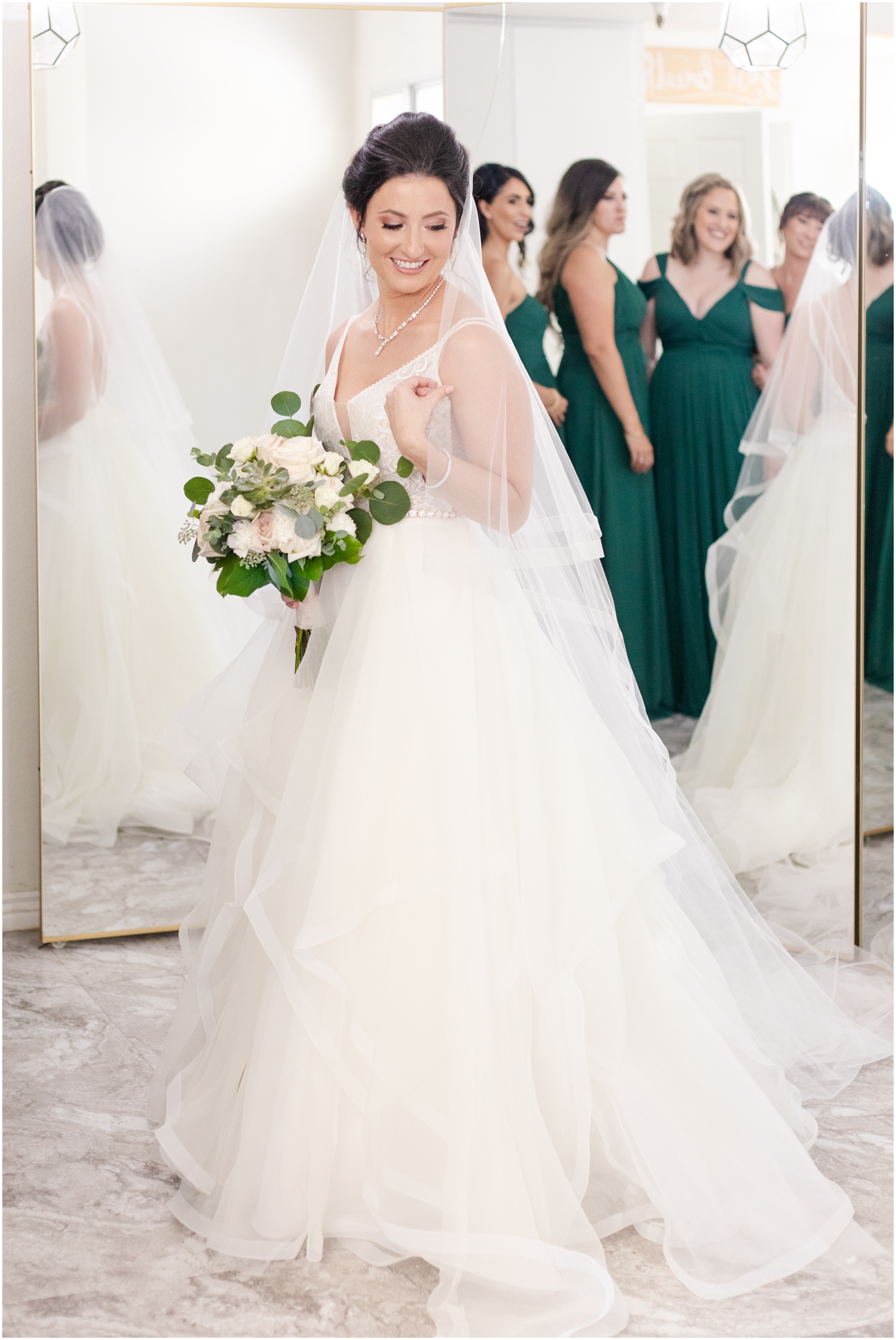 bride smiling at ground in dress while holding bouquet 