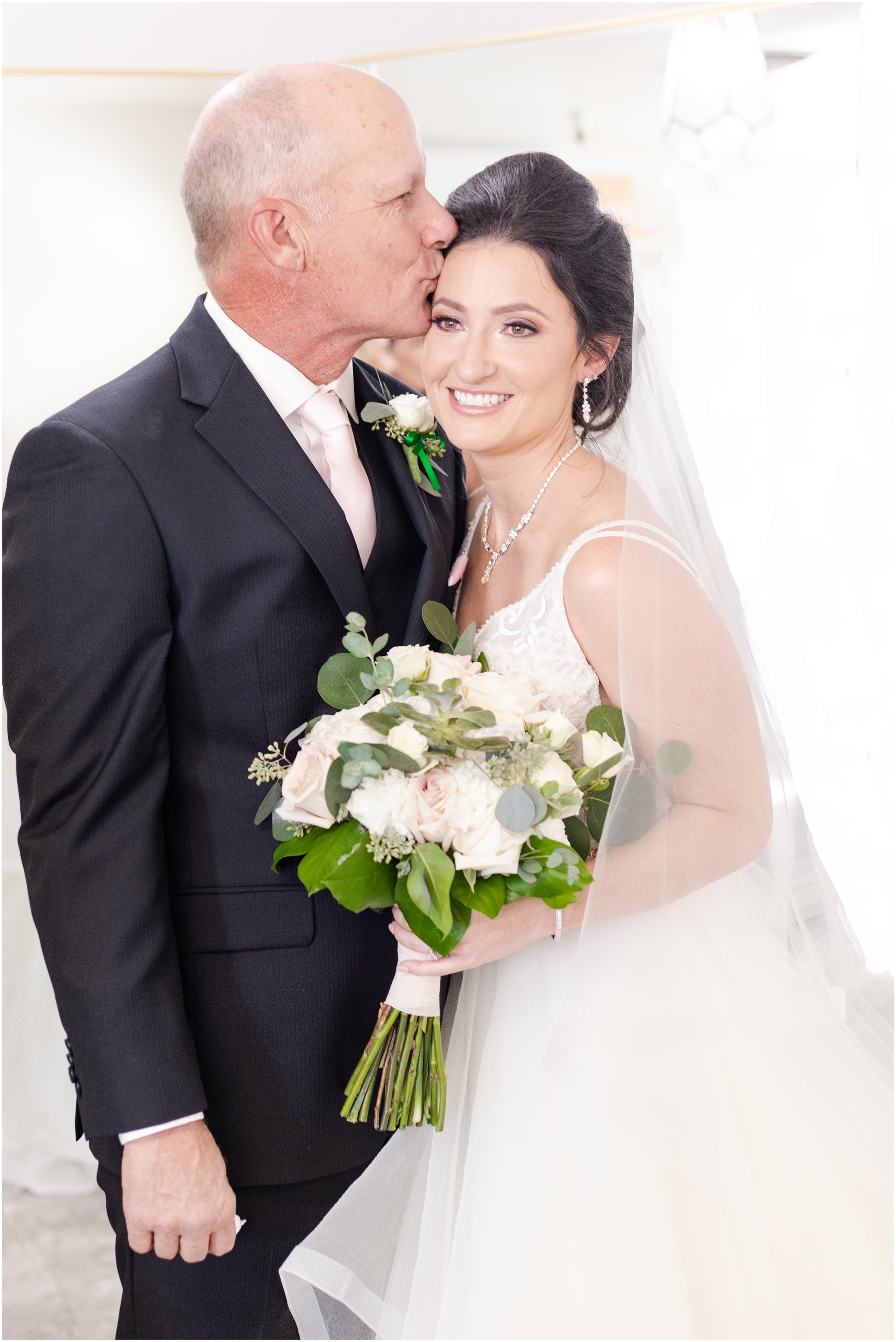 Dad kissing bride's forehead while bride smiles