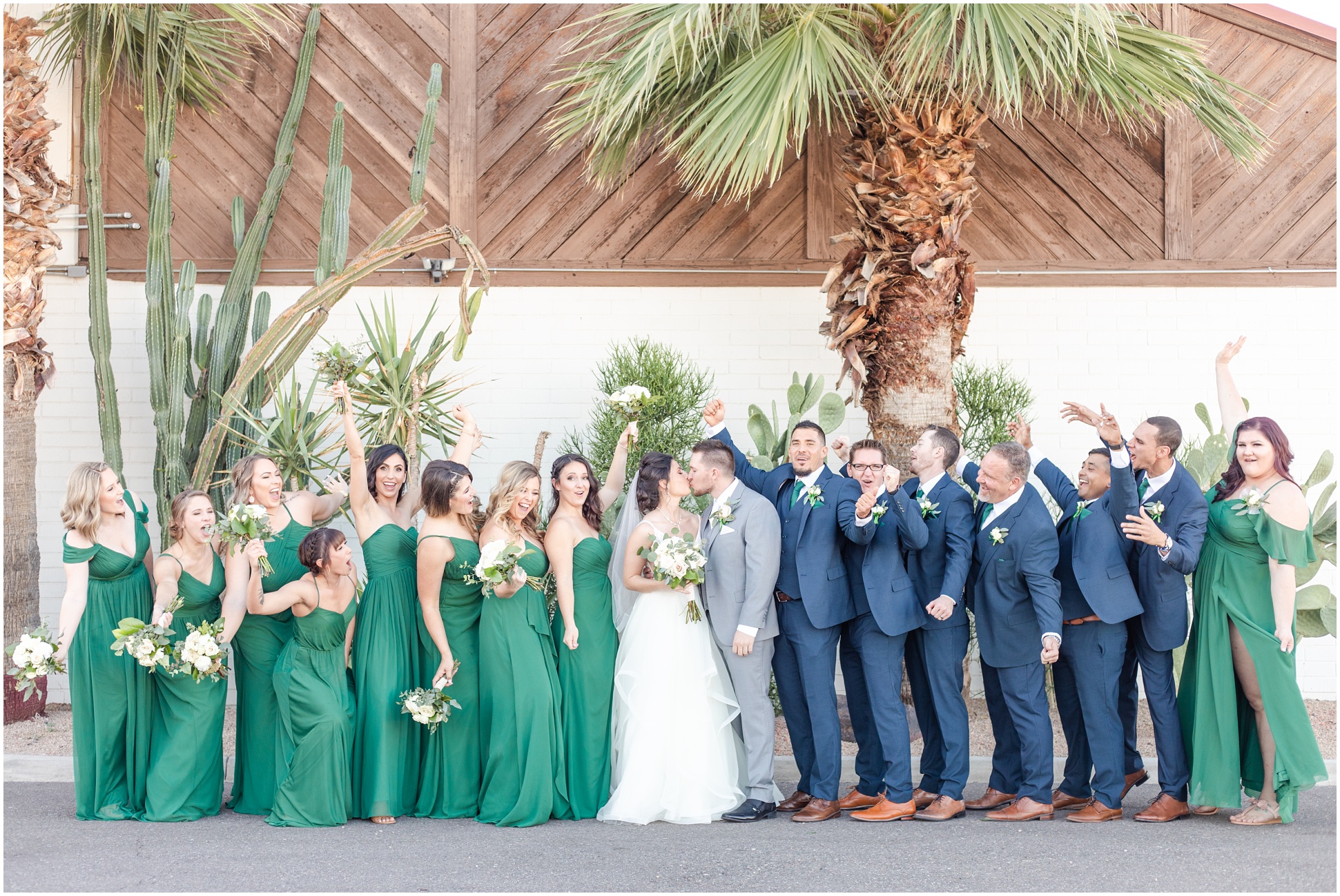 Group photo of Bride and Groom kissing with Groomsmen and Bridesmaids framing them