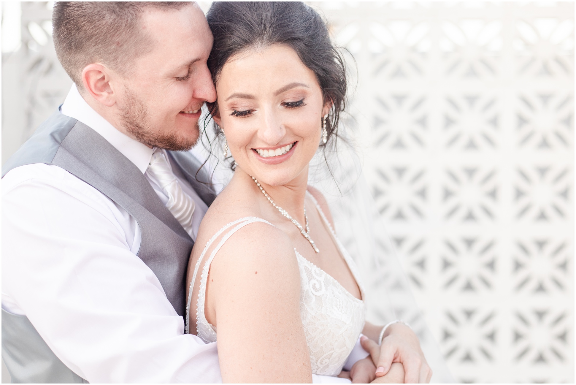 Groom snuggling into bride from behind while they both smile