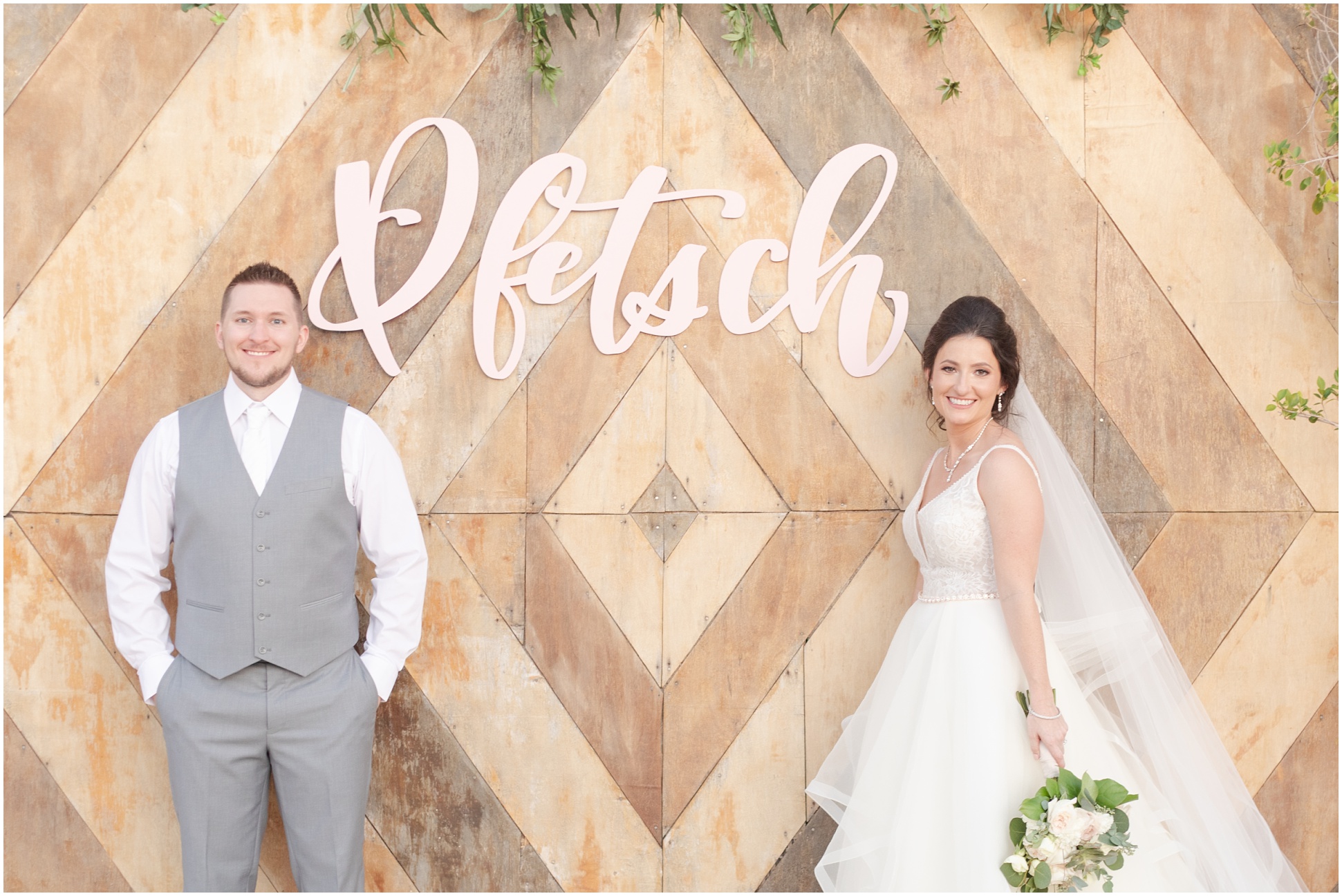 Bride and Groom standing in front of blush pink sign spelling their last name