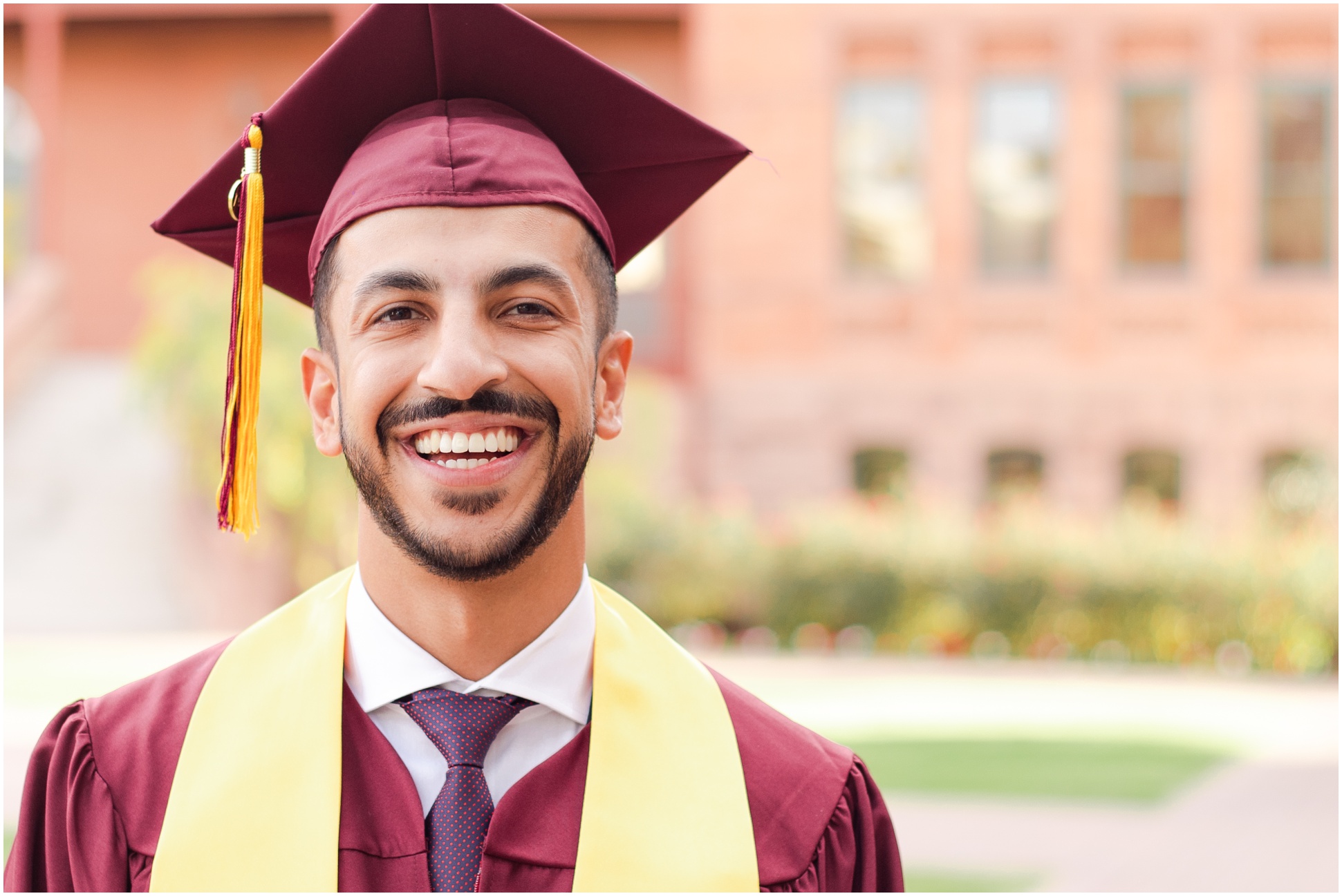 Male college student in graduation attire smiling at camera 