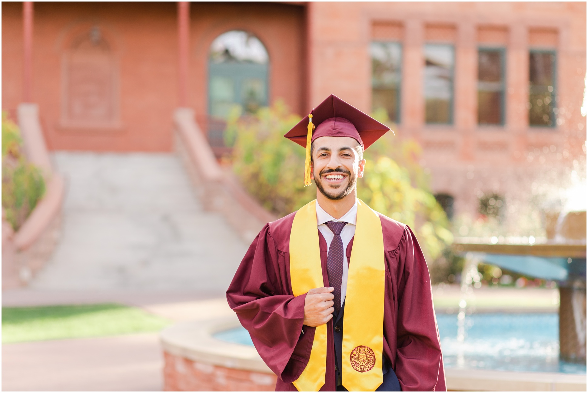 ASU graduate holding academic stole and smiling at camera