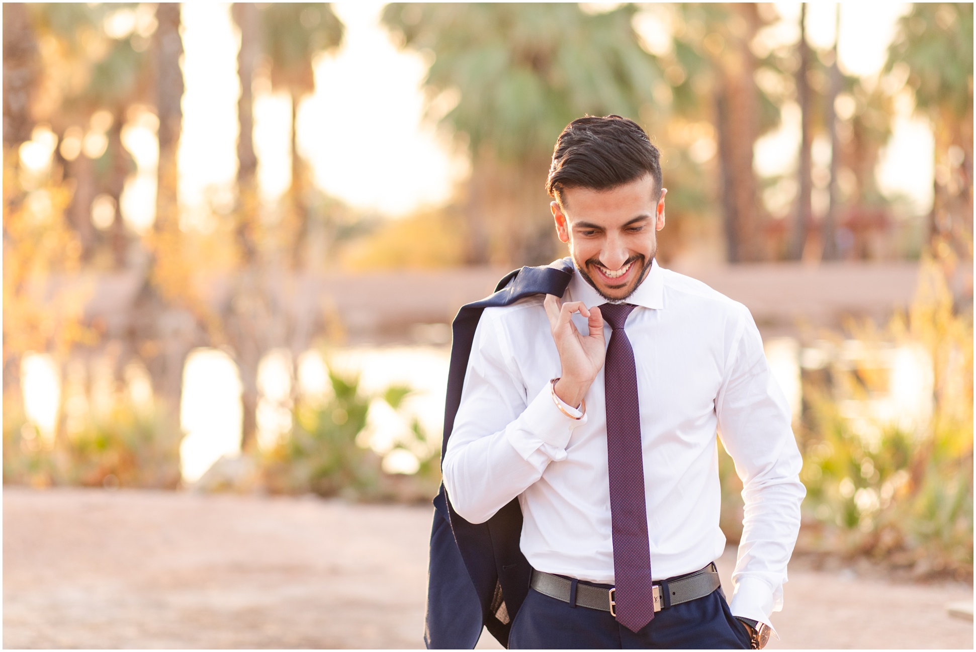 ASU graduate walking towards camera with coat over shoulder while looking at the ground at Popago Park