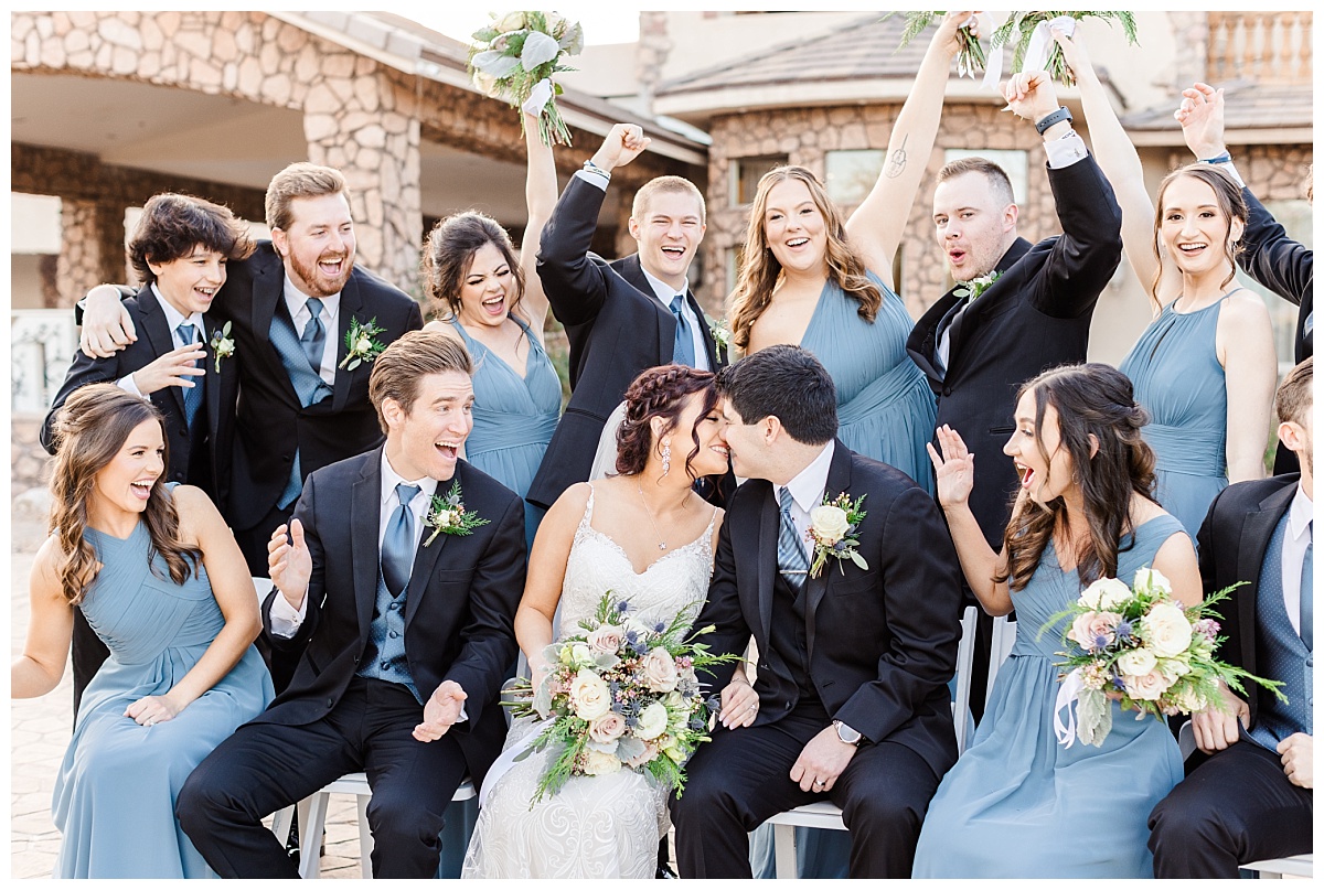 kissing couple with bridal party in black and dusty blue