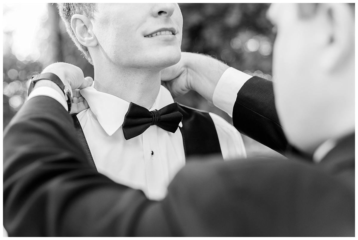Black and white close up of groom getting his bowtie on