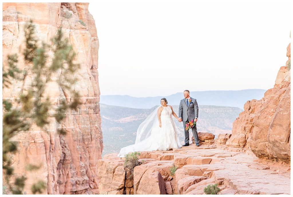 Husband and wife holding hands overlooking Cathedral Rock in Sedona at Sunrise