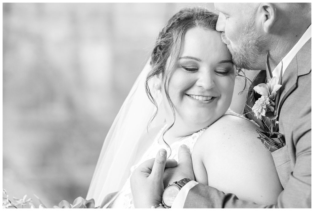 Black and white photo of Bride and groom snuggling on Cathedral Rock in Sedona