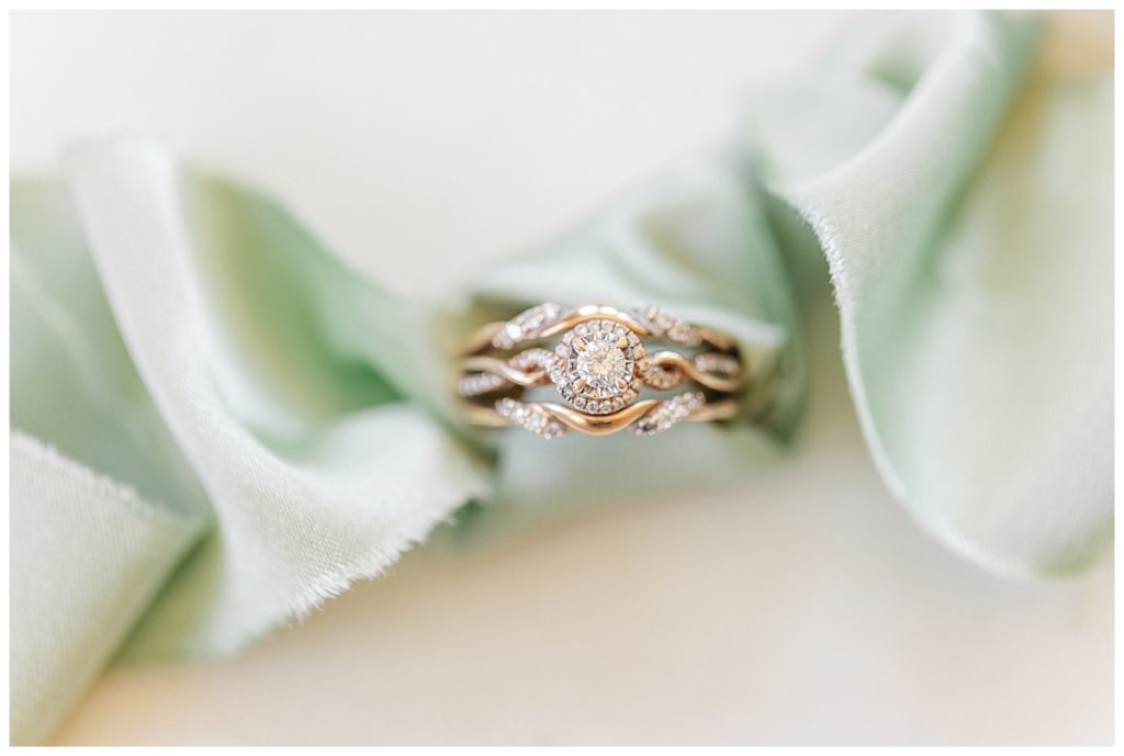 Rose gold wedding ring and band wrapped in a sage green ribbon